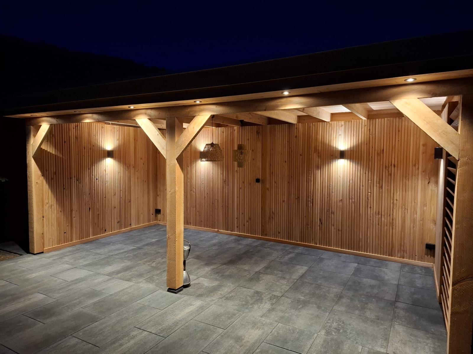 Verlicht houten buitenverblijf met houten wanden, draagconstructie en tegelvloer in de avond
