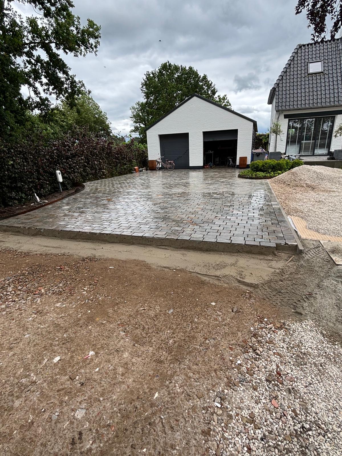Bestraatte oprit voor een woning met een vrijstaande garage