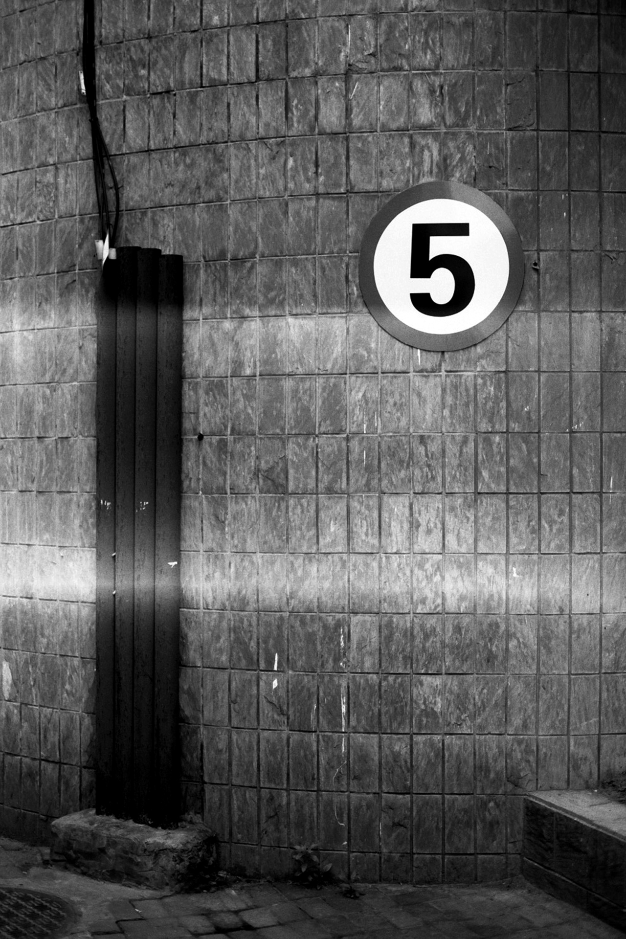 Concrete wall with number five in circle and dramatic shadow cast across surface