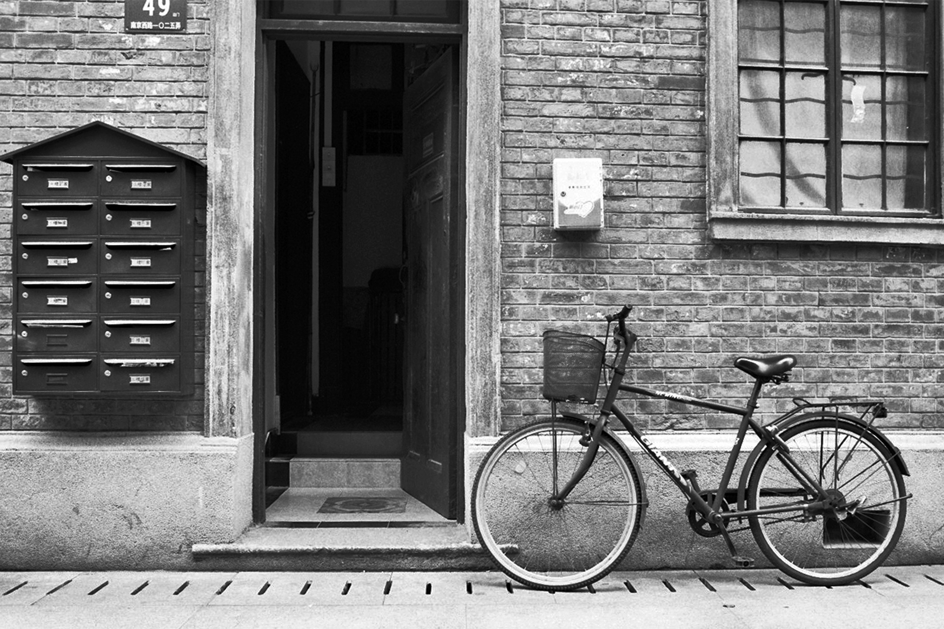 Bicycle parked against building with dark mailbox and dark doorway entrance
