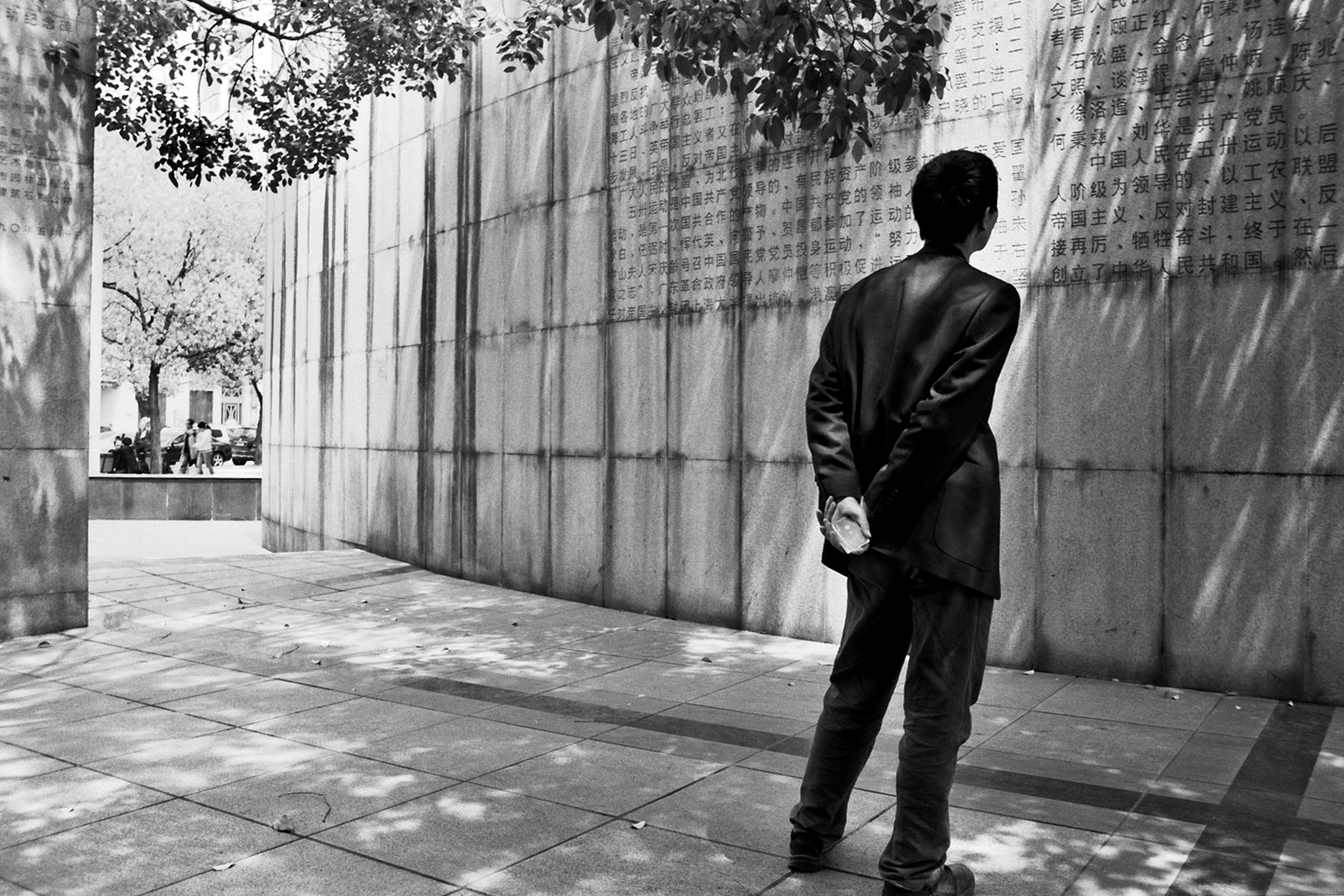 Man standing in modern interior with concrete walls and Chinese text shadows