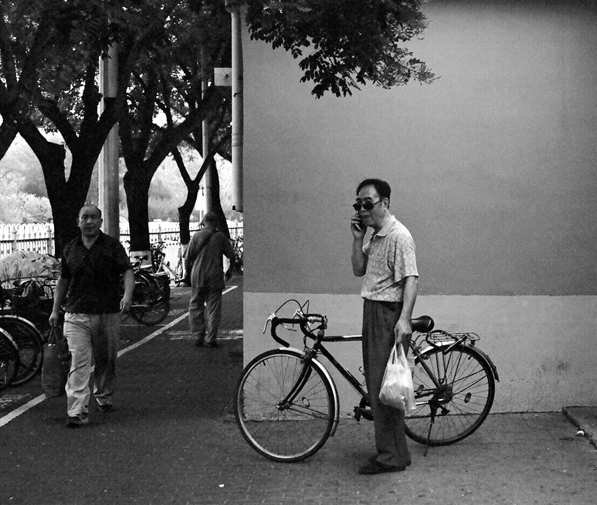 Man with bicycle and public phone booth against neutral wall background