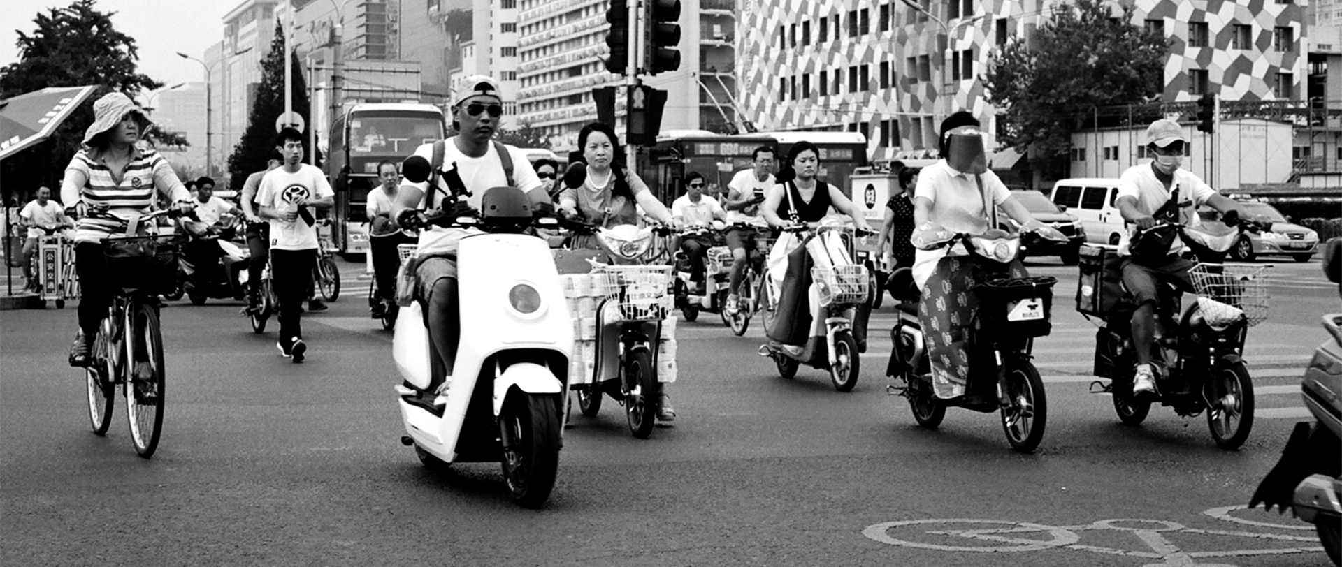 Street scene with people on scooters bicycles and mopeds in busy urban area