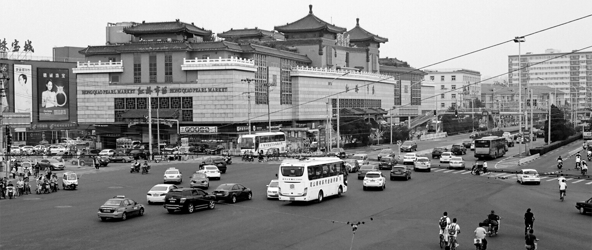 Wide urban street scene with pearl market building and multiple vehicles in traffic