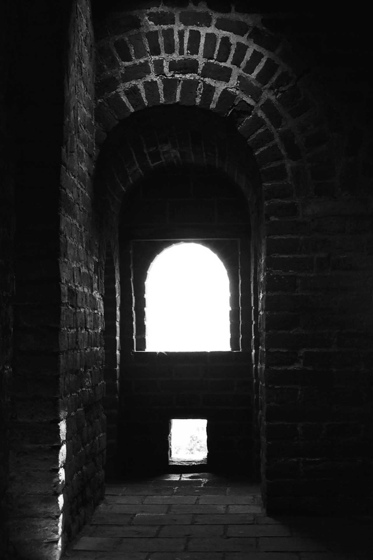 Dark interior of Great Wall fortification passage showing arched brick tunnel and dramatic light