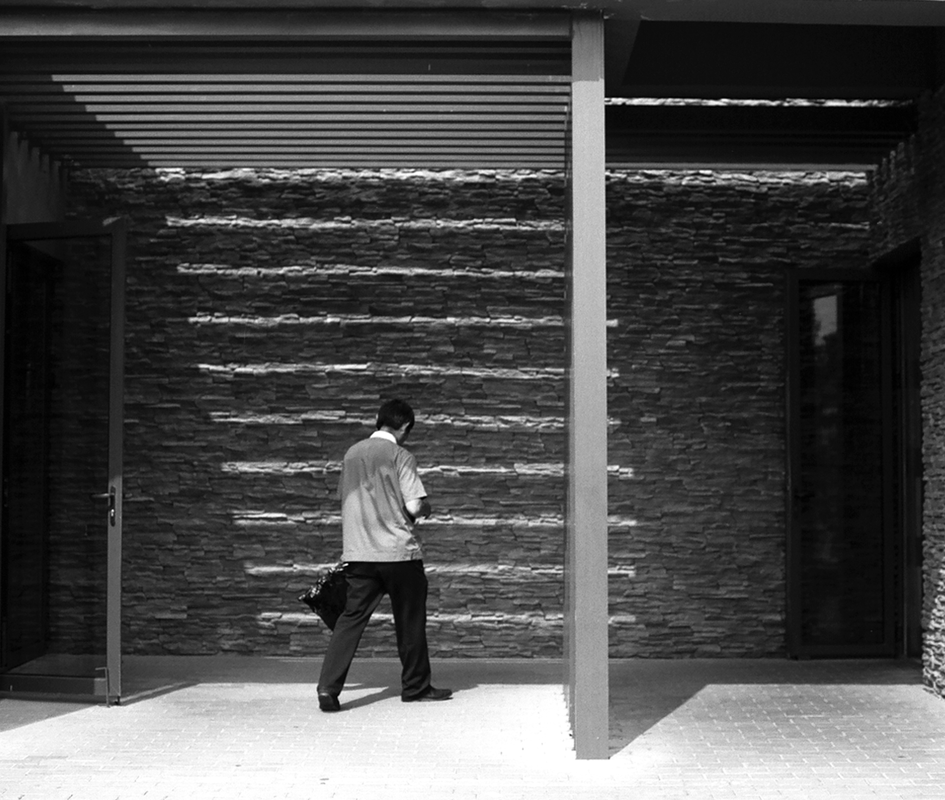 Modern architectural courtyard with brick walls and man in white shirt silhouetted walking