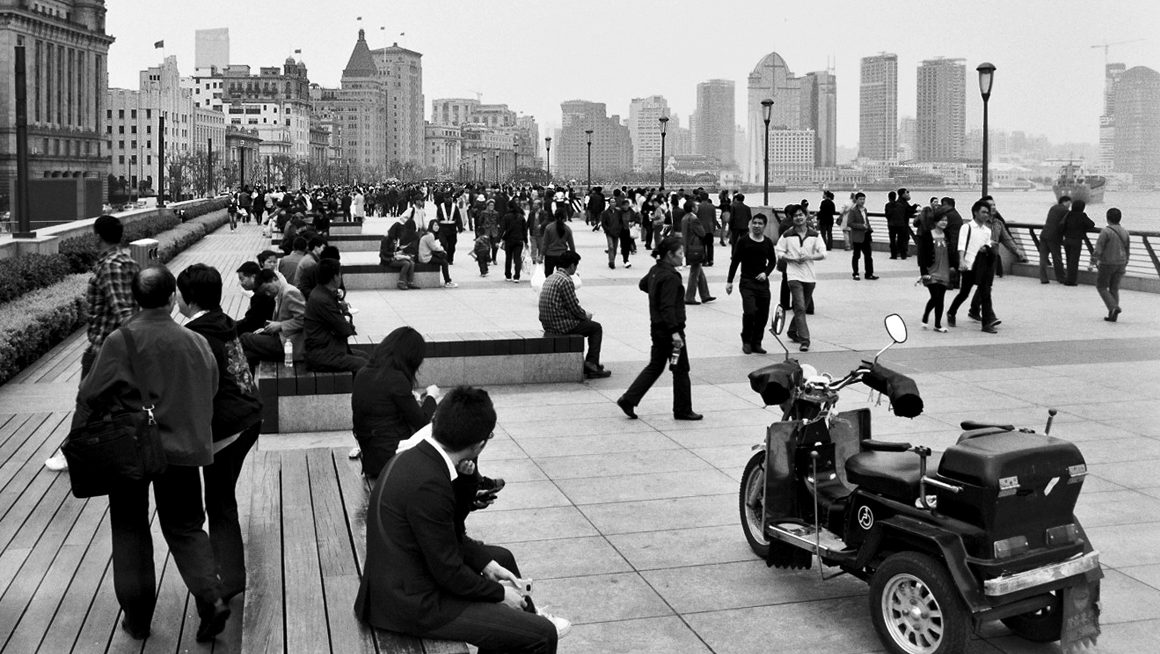 Crowded Shanghai Bund waterfront promenade with pedestrians and skyline across the river