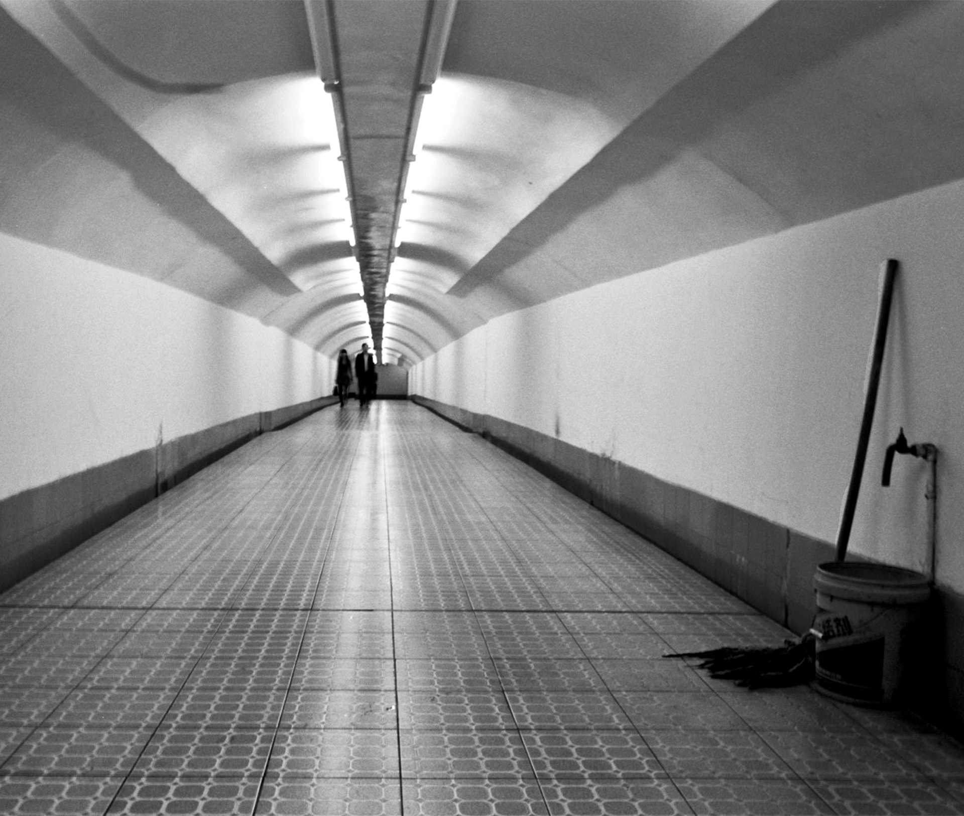 Modern tunnel interior with dramatic receding perspective and fluorescent ceiling lighting