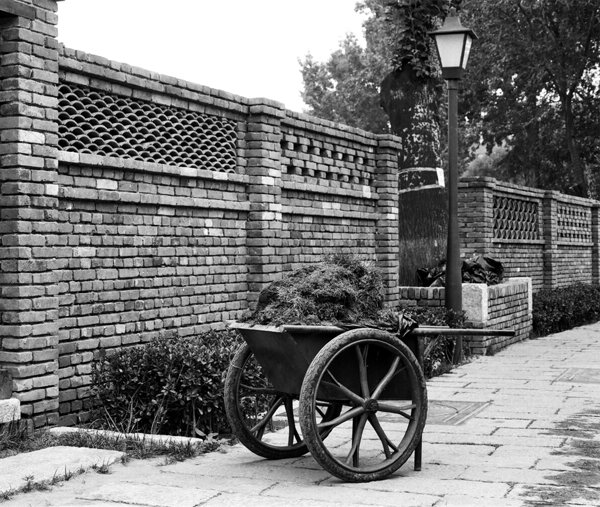 Brick architectural wall with diamond-pattern lattice work ventilation and street lamp in garden