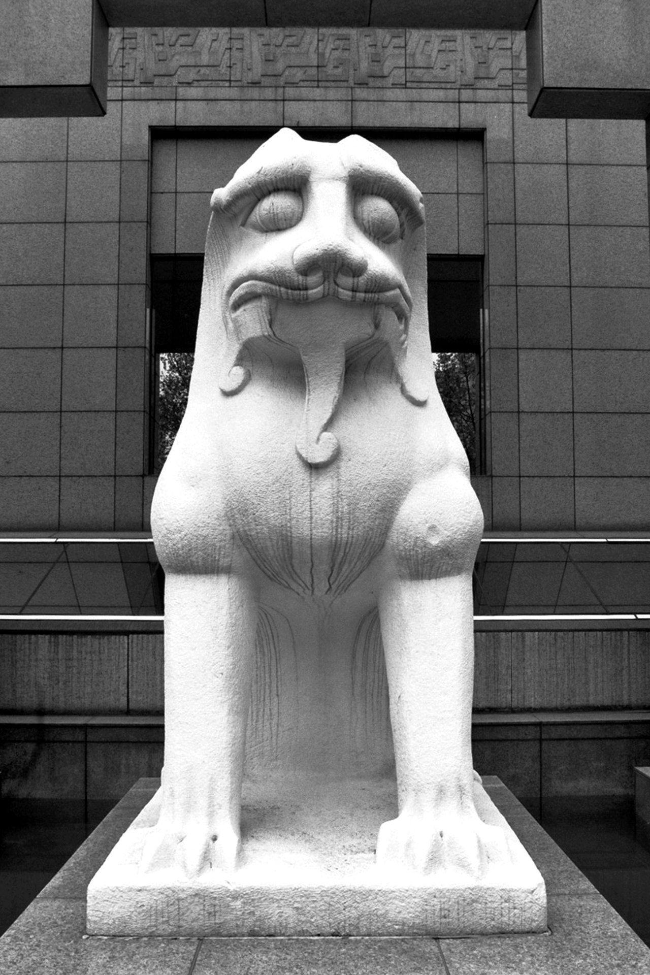 Large white stone foo dog guardian statue centered against modern building facade background