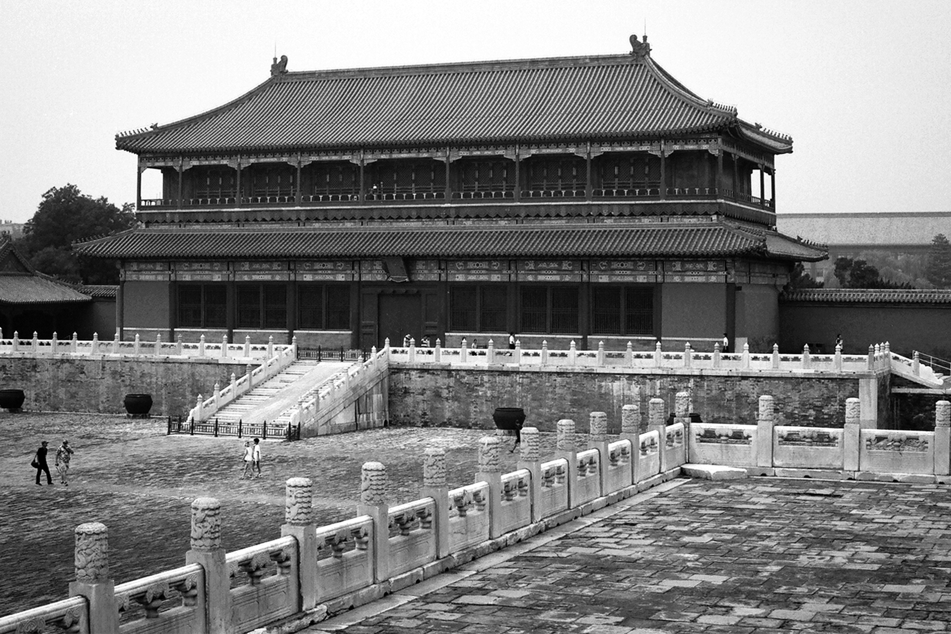 Large imperial courtyard with traditional architecture stone balustrades and people walking in plaza
