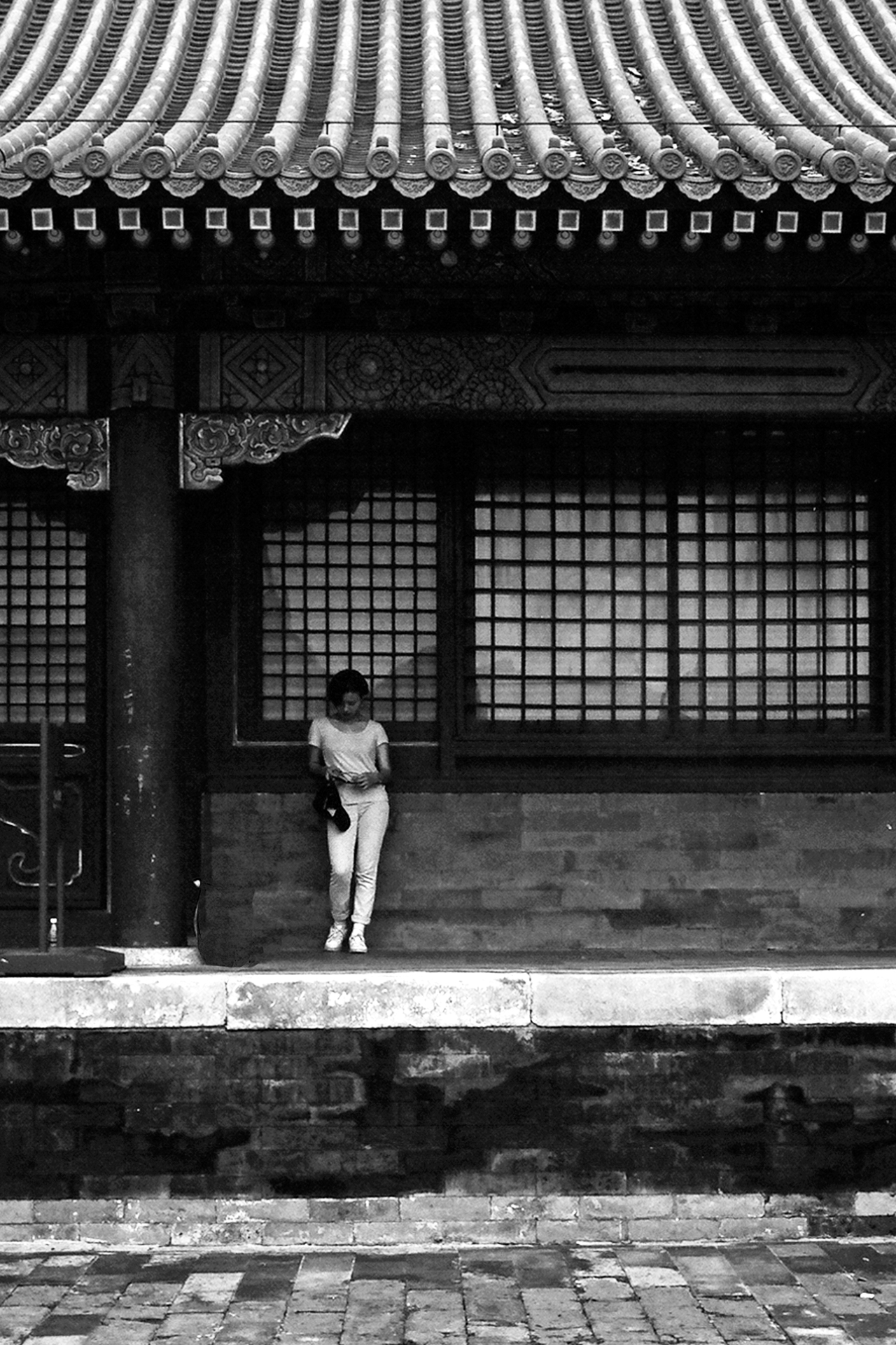 Woman standing under traditional roof with elaborate lattice work windows and ceramic roof tiles