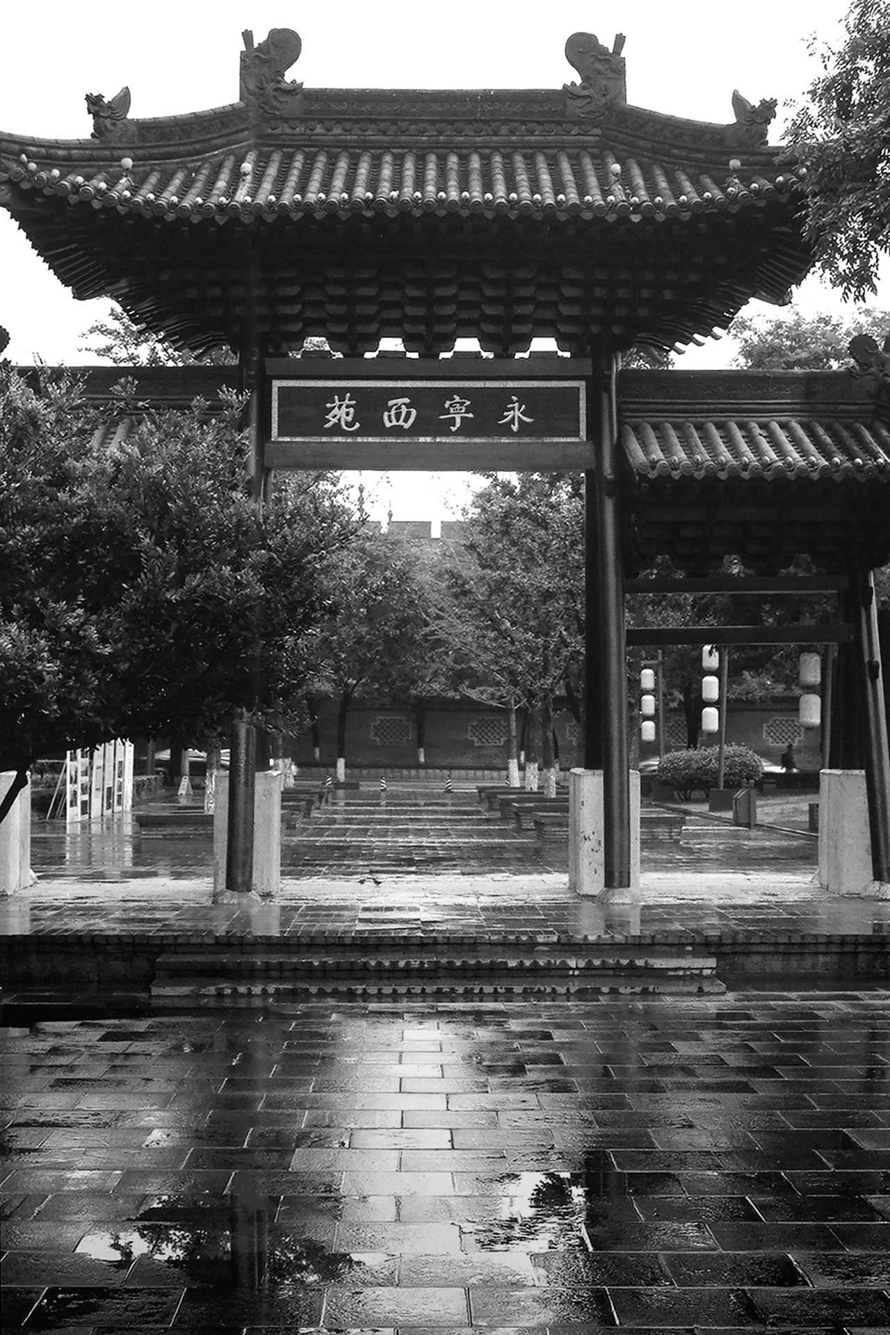 Traditional Chinese pavilion with elaborate curved roof and carved stone details with wet stone courtyard