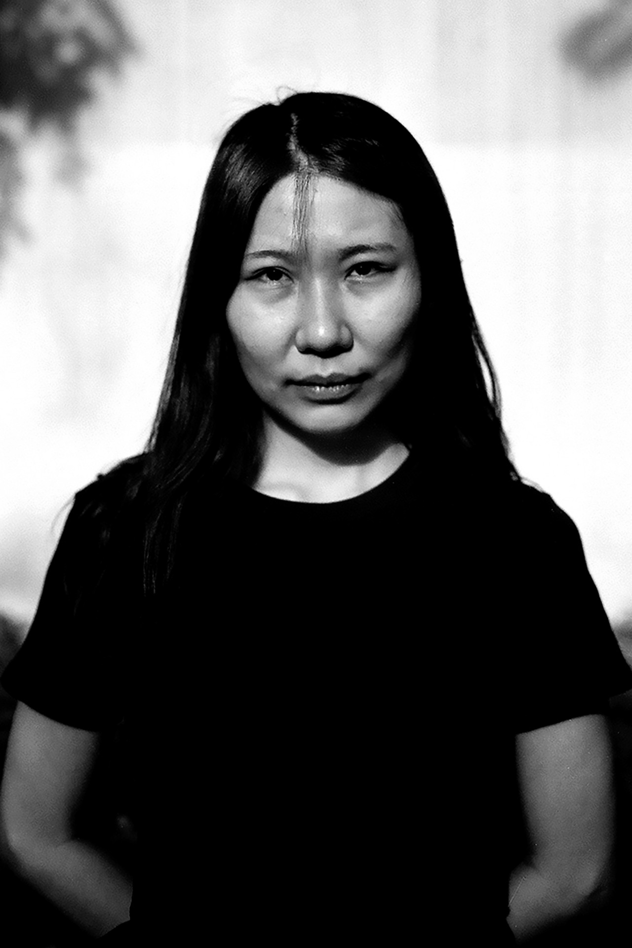 Portrait of woman with long black hair wearing black shirt against neutral blurred background