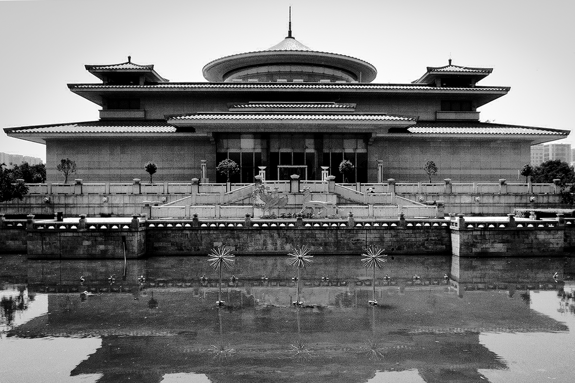 Traditional Chinese palatial building with multiple curved roofs reflected in water with ornamental railings