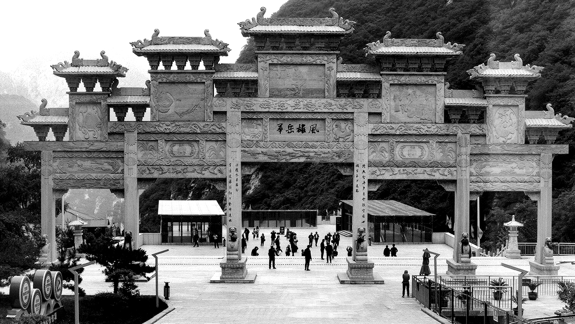 Grand ceremonial temple gate with ornate stone lions and multiple tiers with curved roofs and crowds