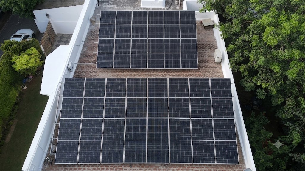 Aerial view of two neatly aligned solar arrays installed on a brick residential rooftop