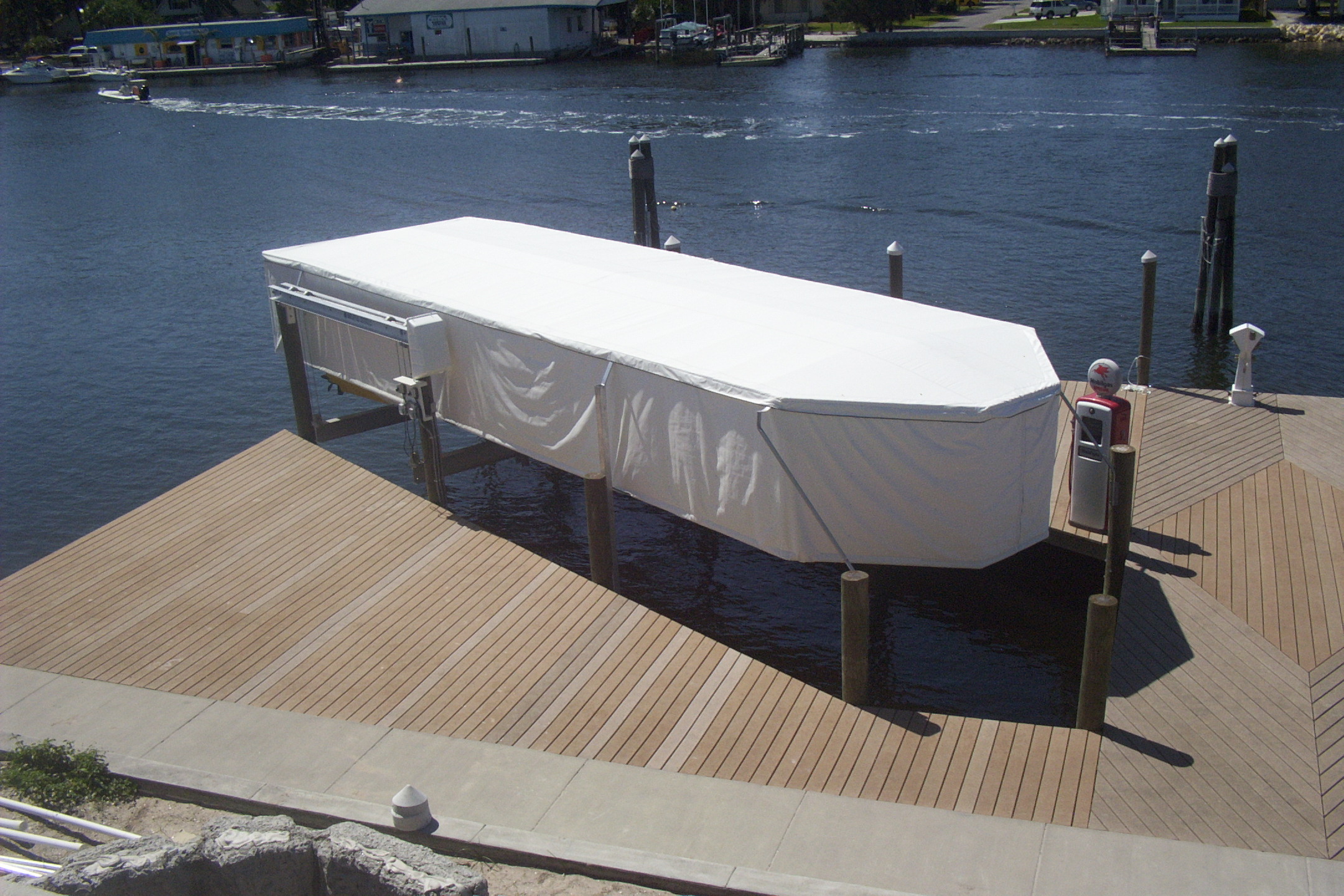 White Touchless Cover fully closed over a large boat on a Florida waterfront dock