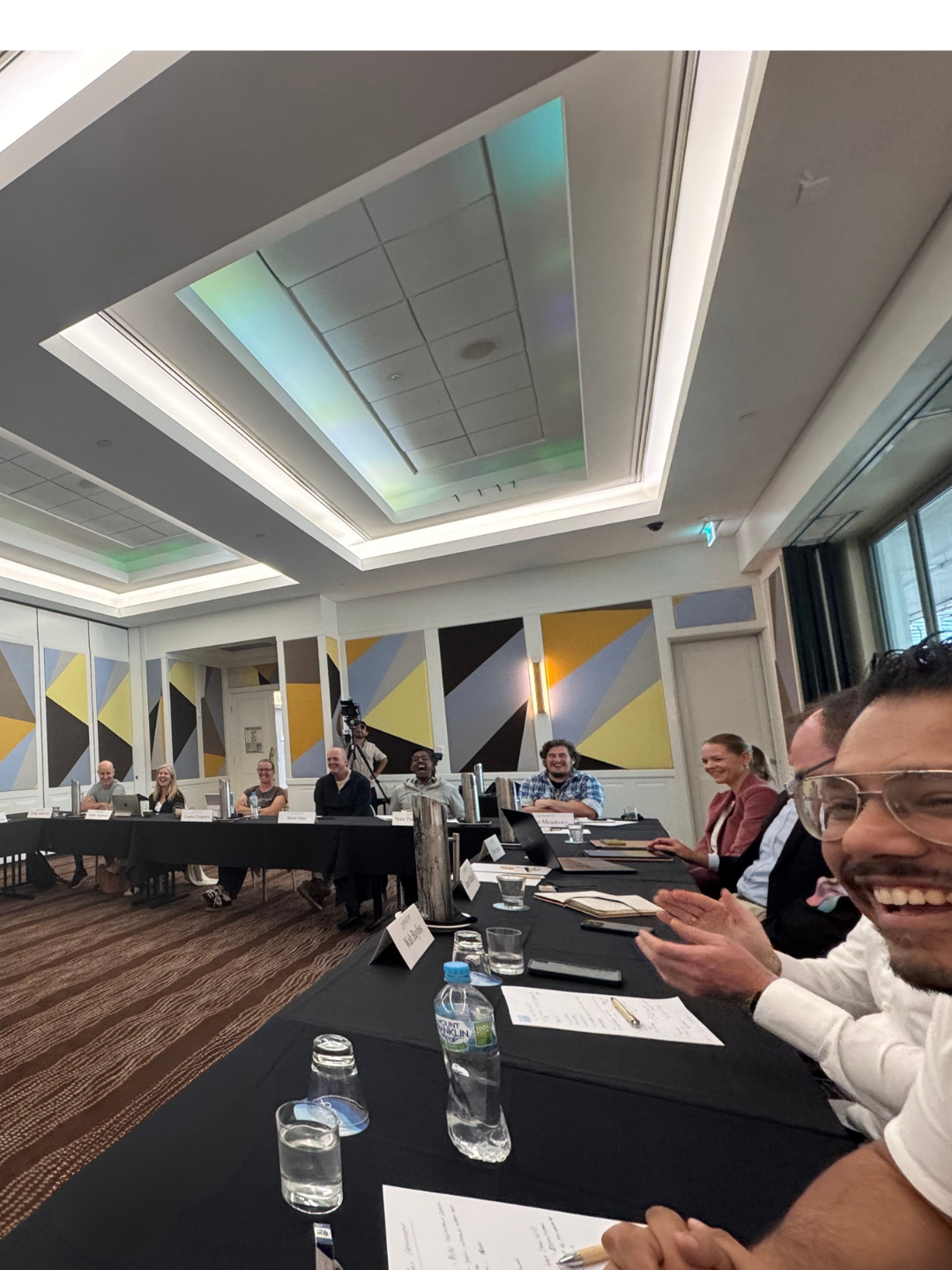 Collective members seated around a conference table during a structured mastermind session in a professional hotel meeting room.