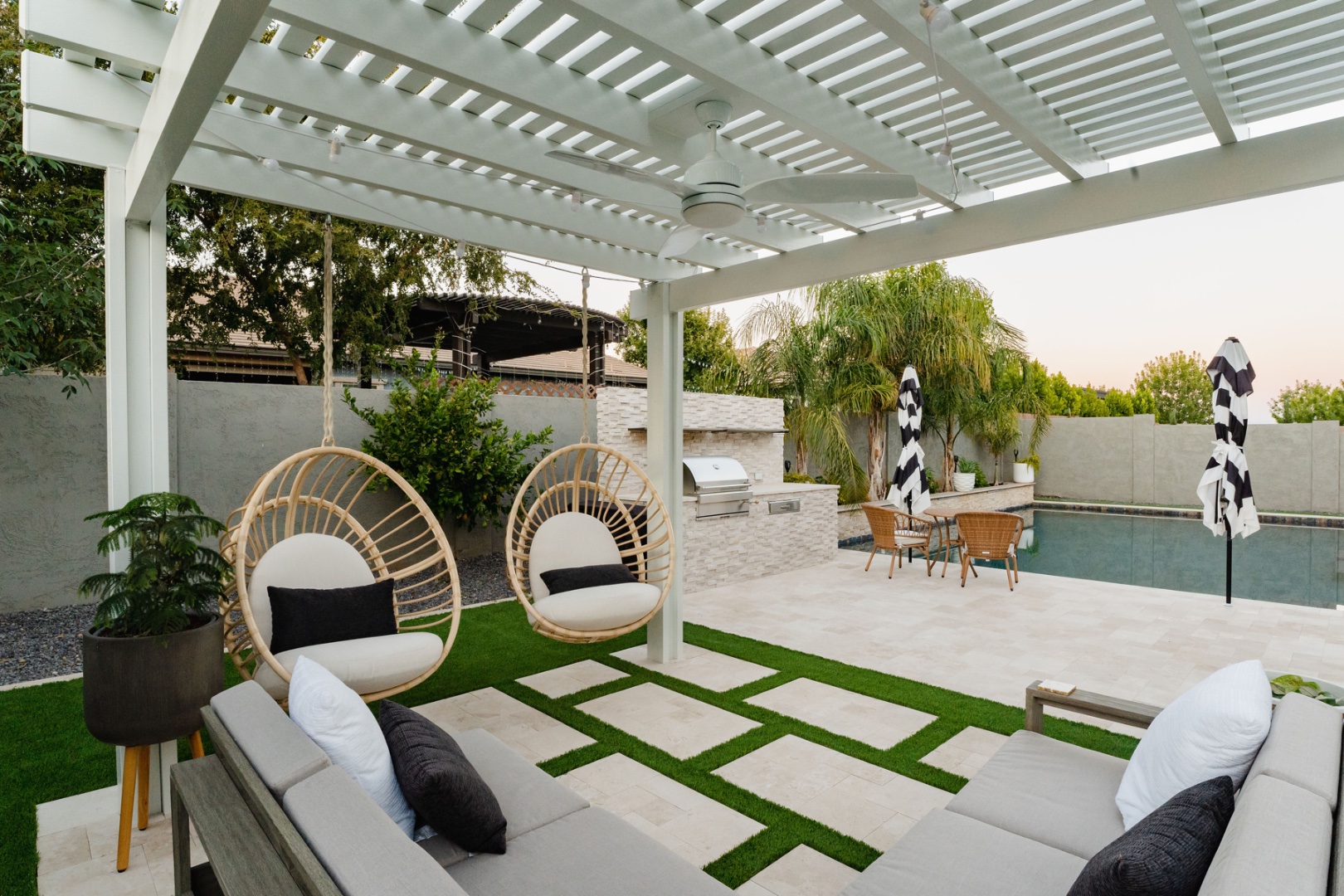 Under-pergola view with hanging egg chairs and pool — Comstock Dr