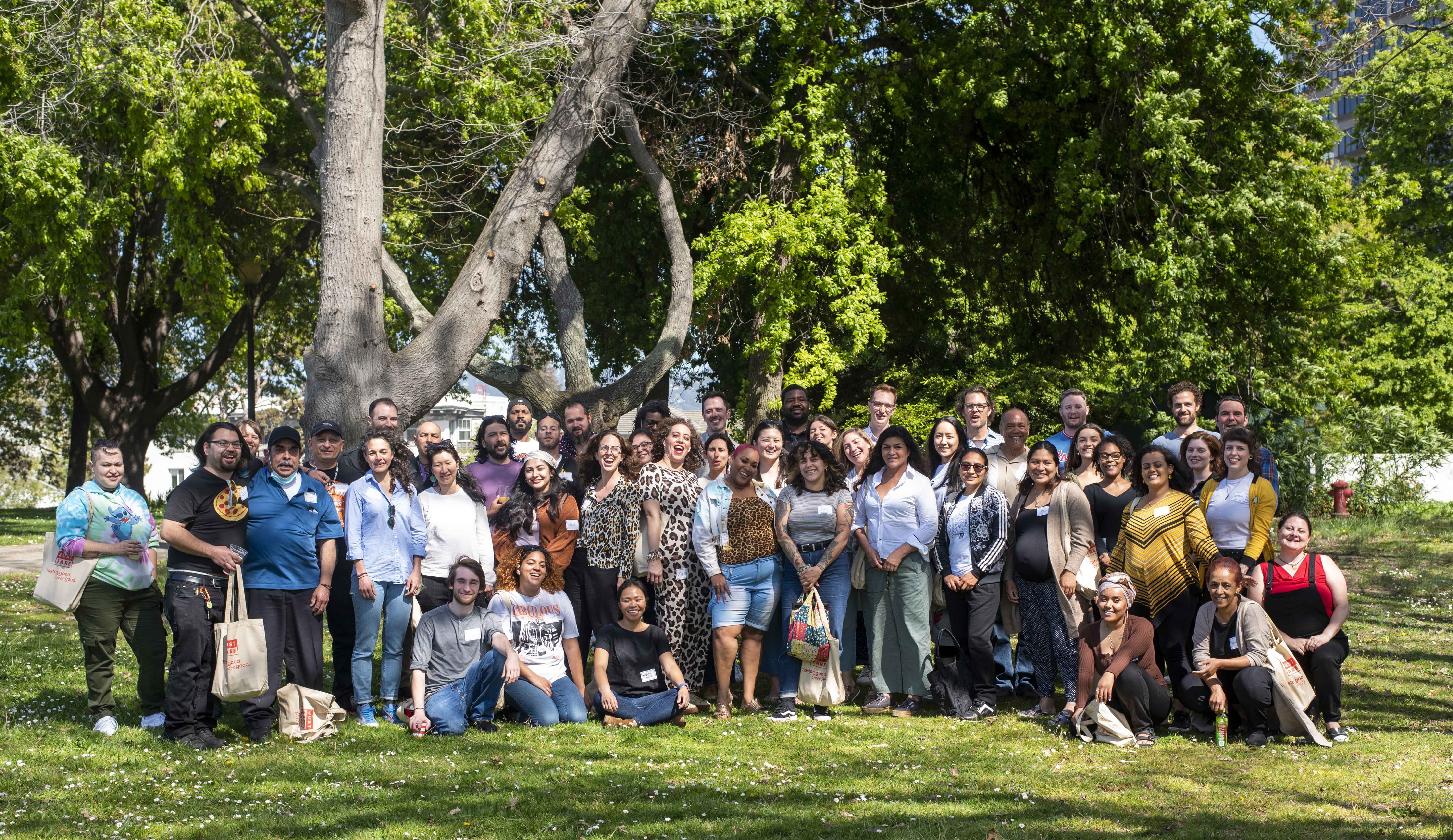 Just Fare team members and community partners smiling together under a tree in a San Francisco park