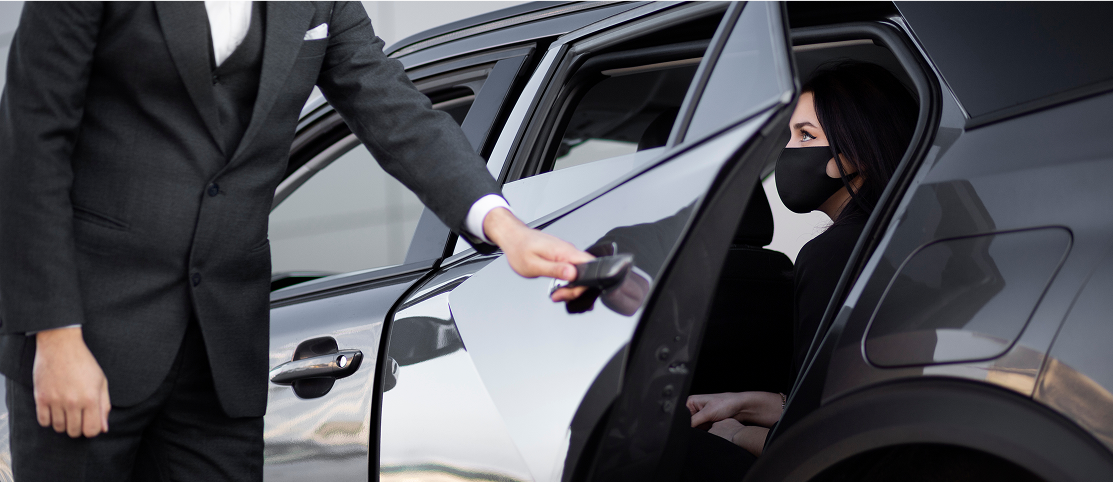 Chauffeur in suit opening car door for a passenger