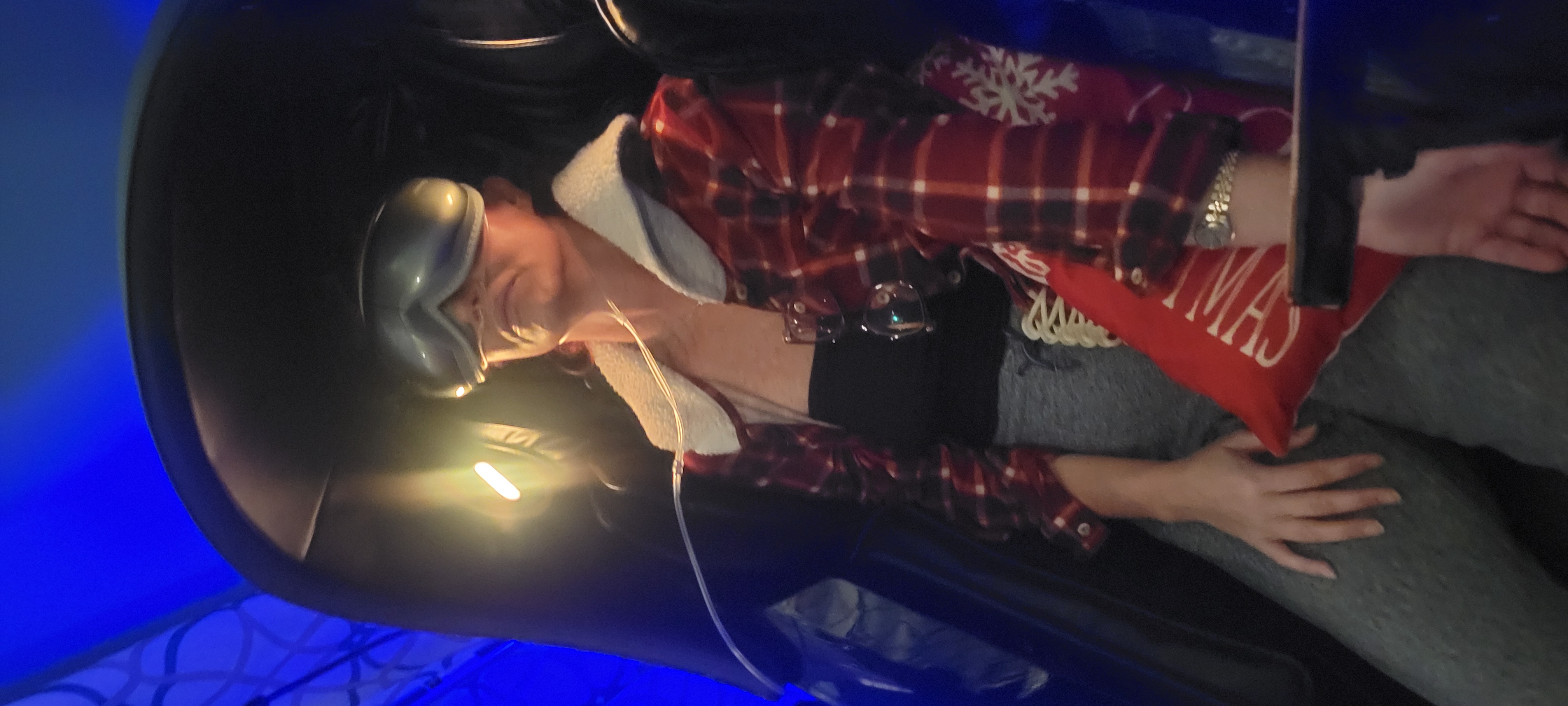 A client relaxing in a massage chair wearing light-therapy goggles during a treatment