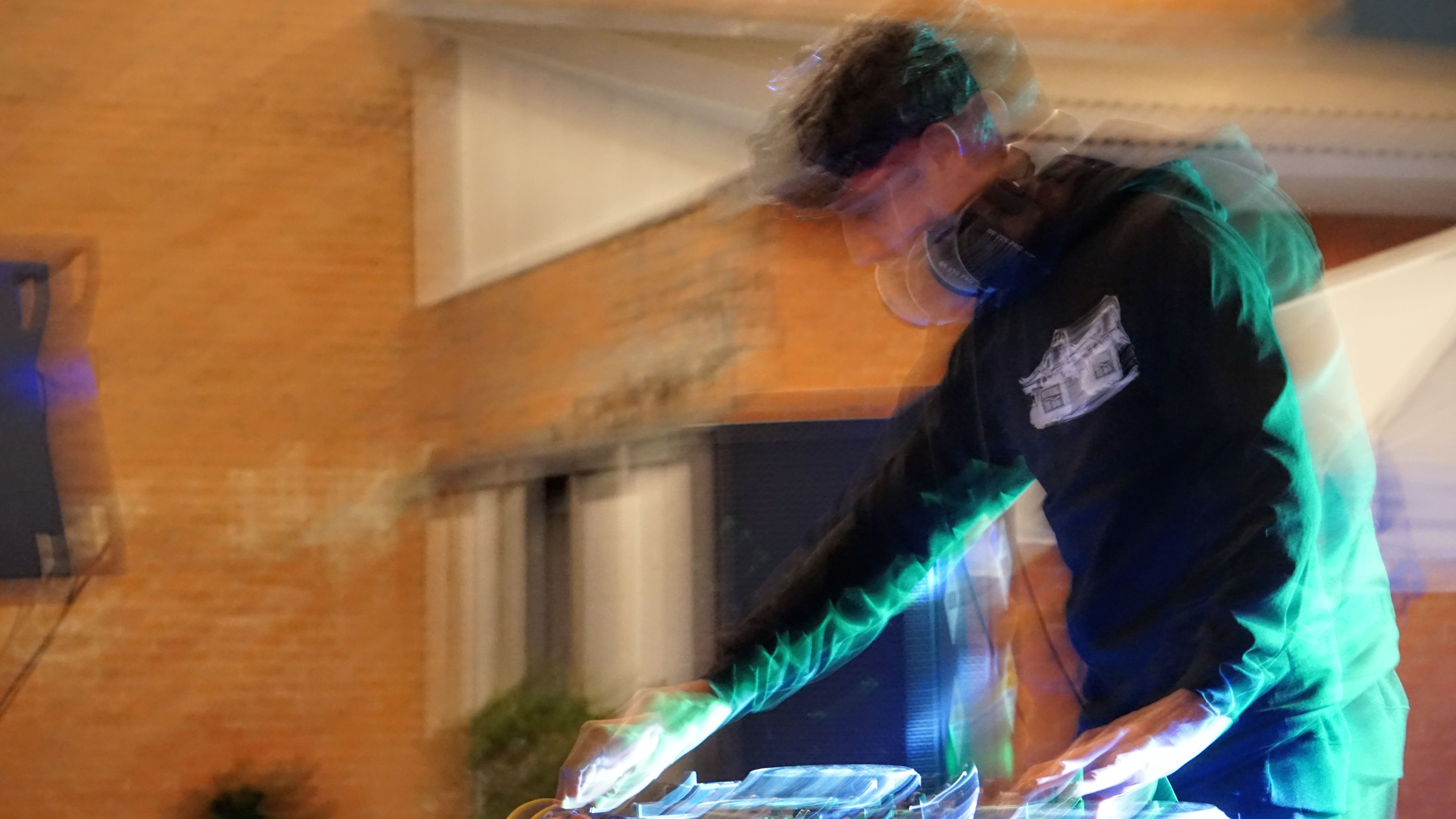 DJ performing with motion blur and teal lighting