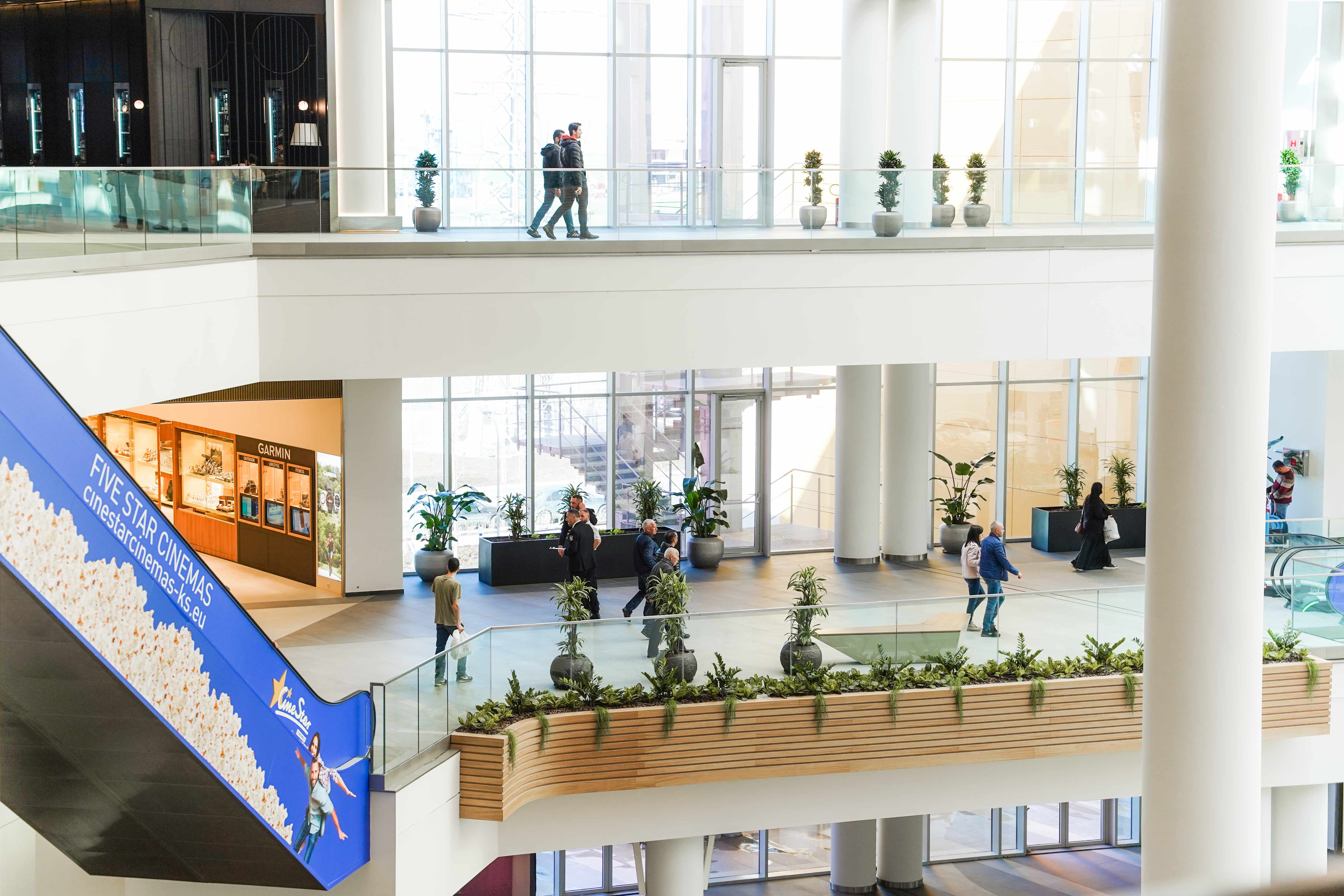 Atrio a più livelli di un grande centro commerciale con fioriere integrate nel percorso
