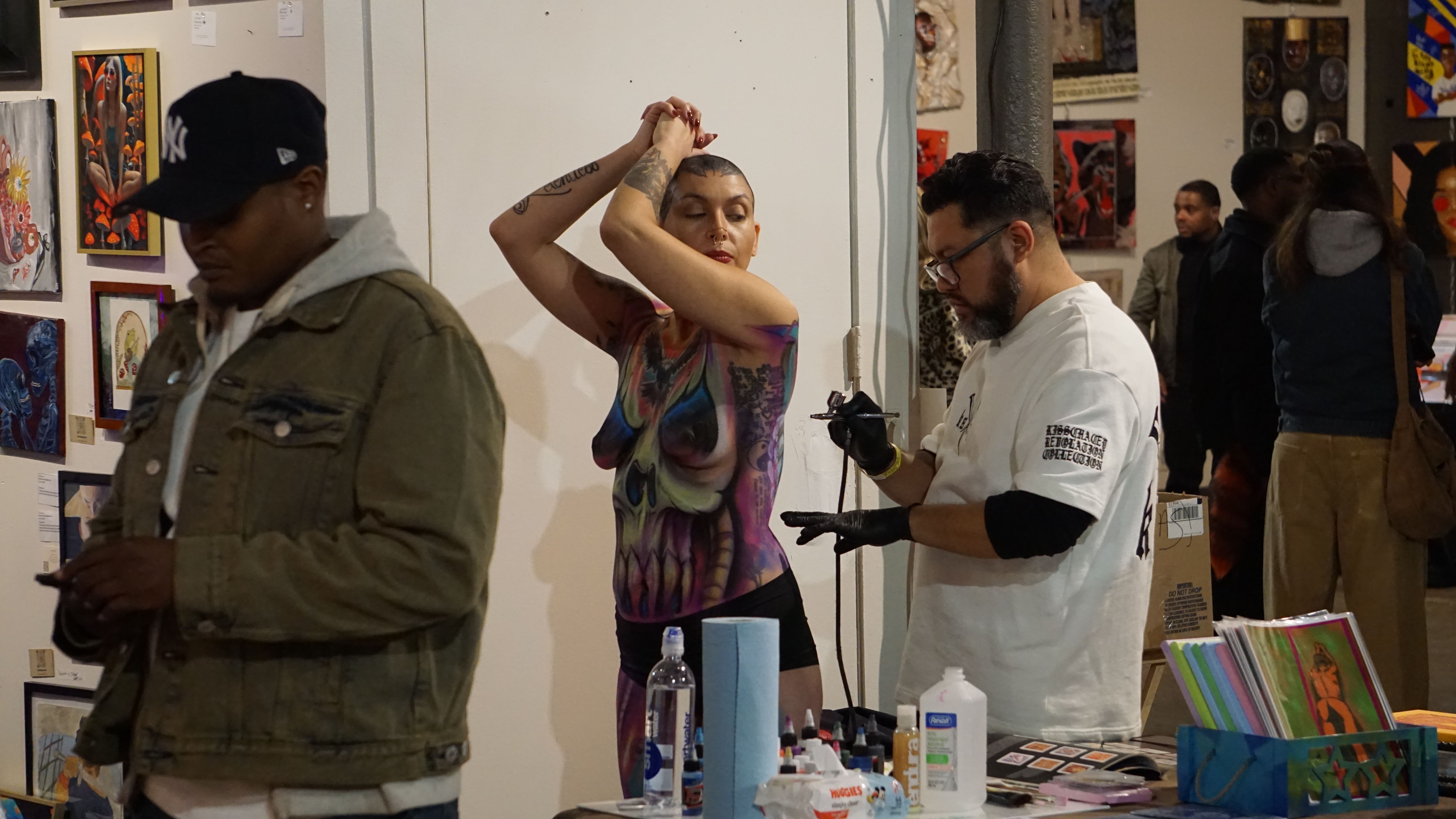 Body painting artist creating colorful skull design on model