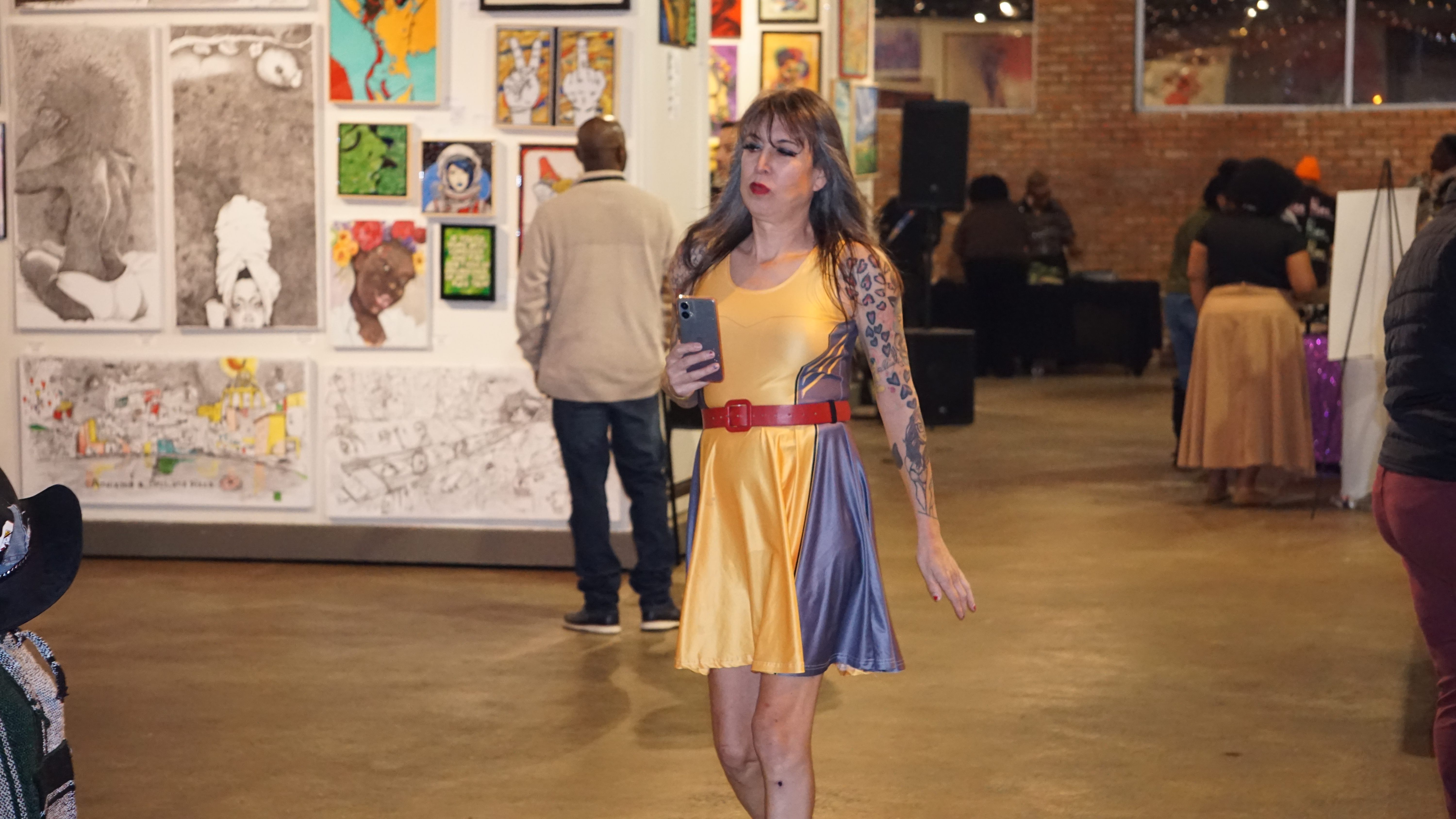 Stylish attendee in yellow dress walking through gallery