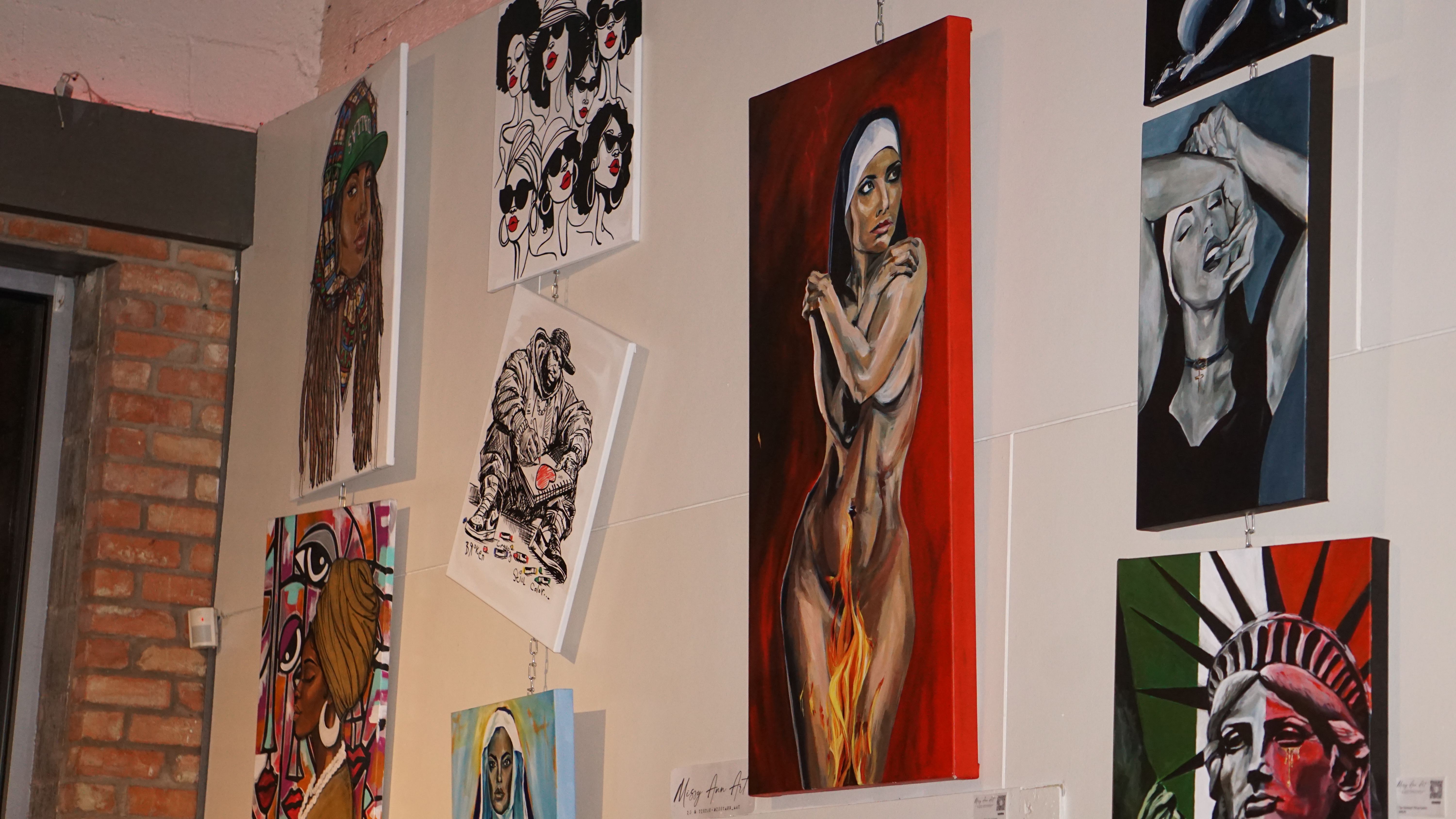 Gallery wall with diverse portrait paintings and artwork