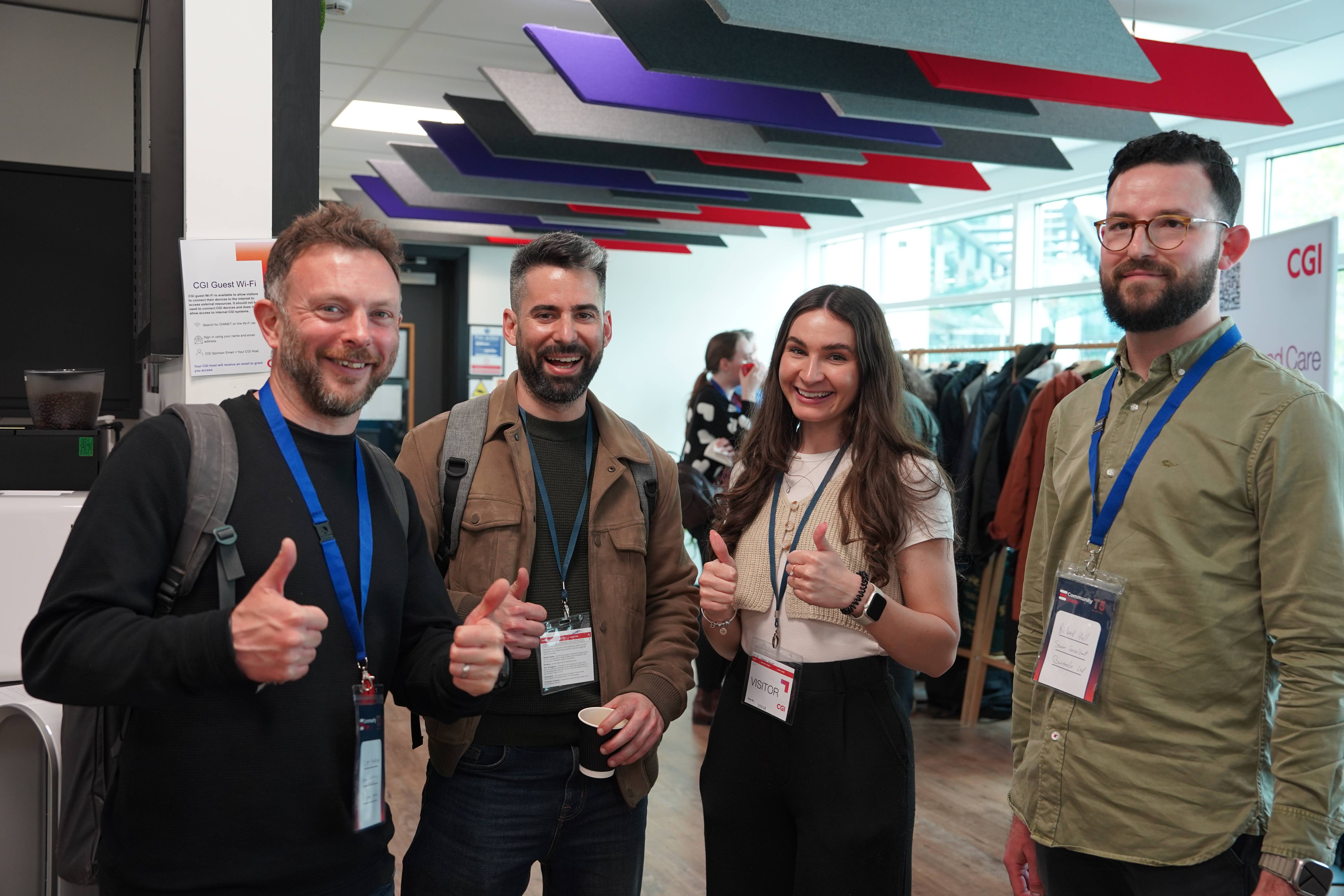 Four attendees posing with thumbs up at a CGI-hosted event