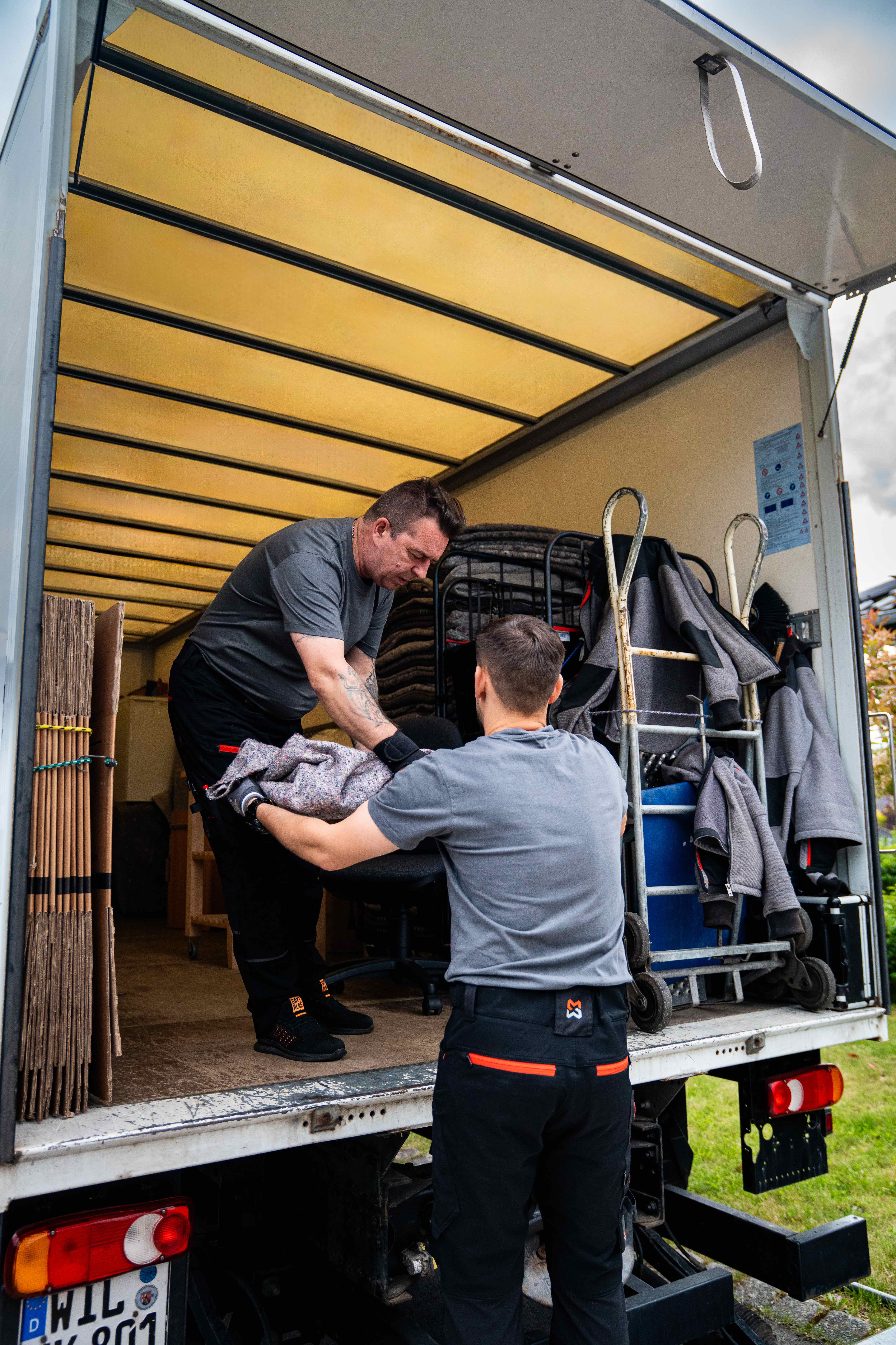 Koch Umzüge Mitarbeiter verladen Bürostuhl in den Umzugswagen