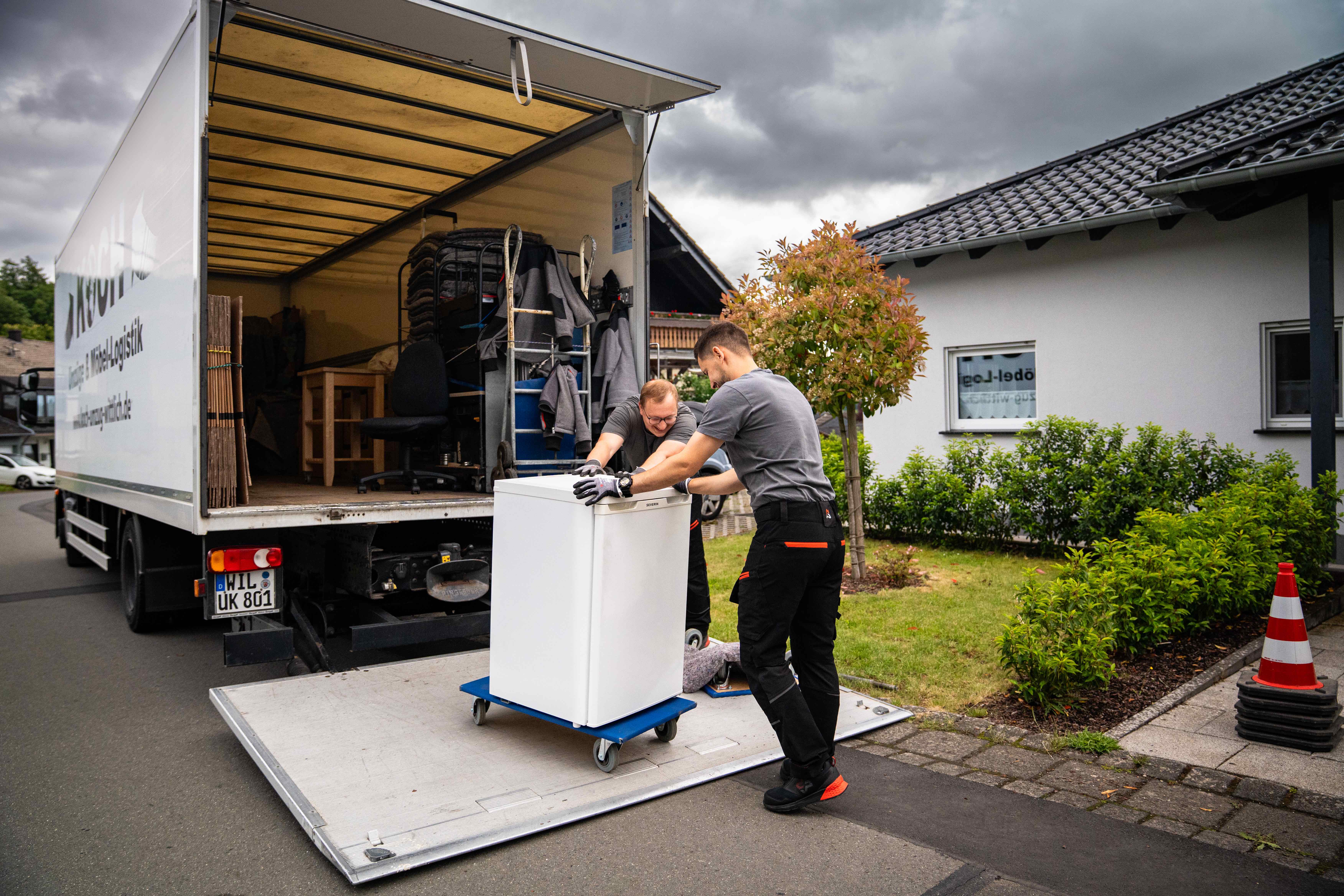 Koch Umzüge Mitarbeiter laden Waschmaschine über Hebebühne in den LKW