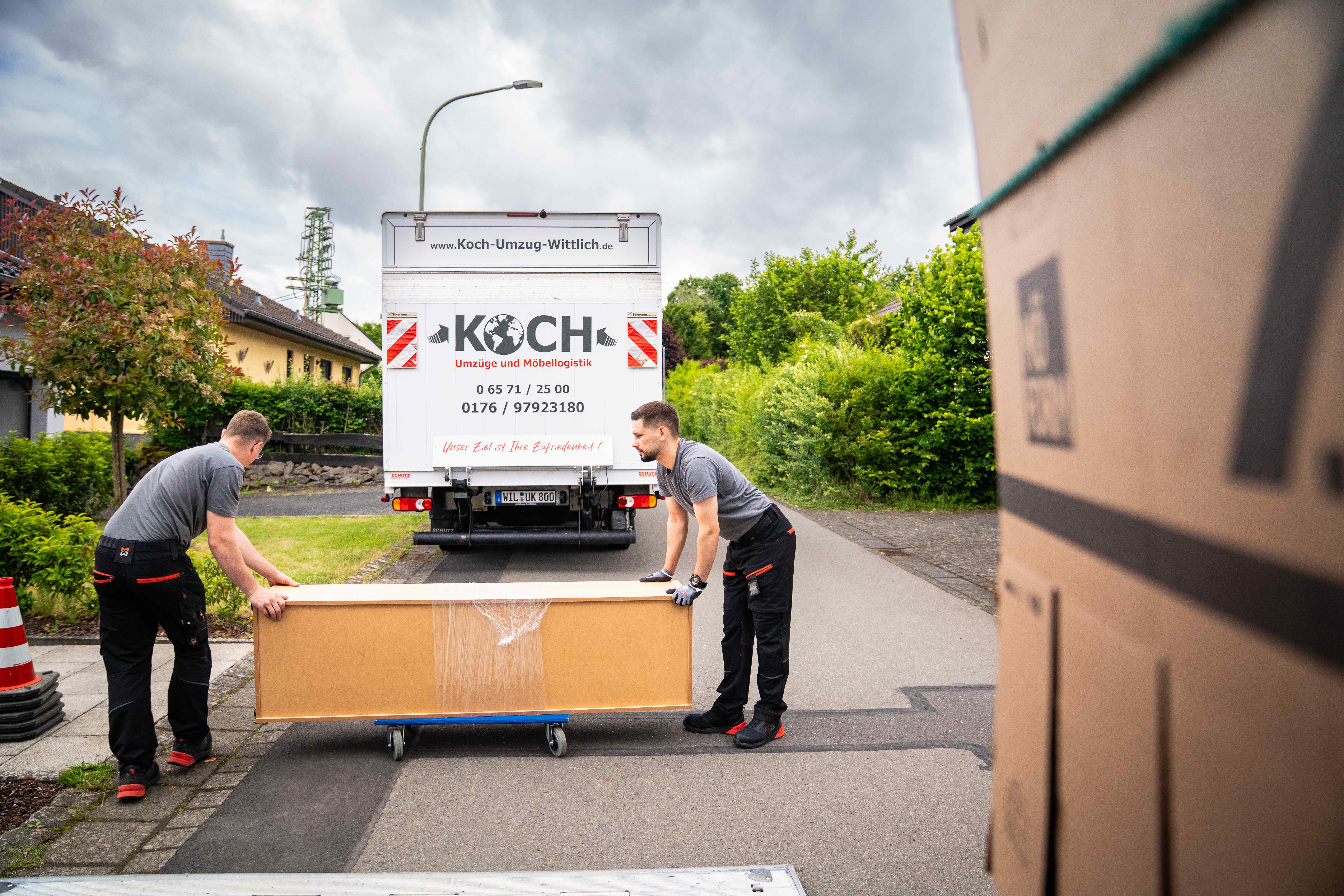 Zwei Koch Umzüge Mitarbeiter tragen verpackten Schrank zum Umzugswagen