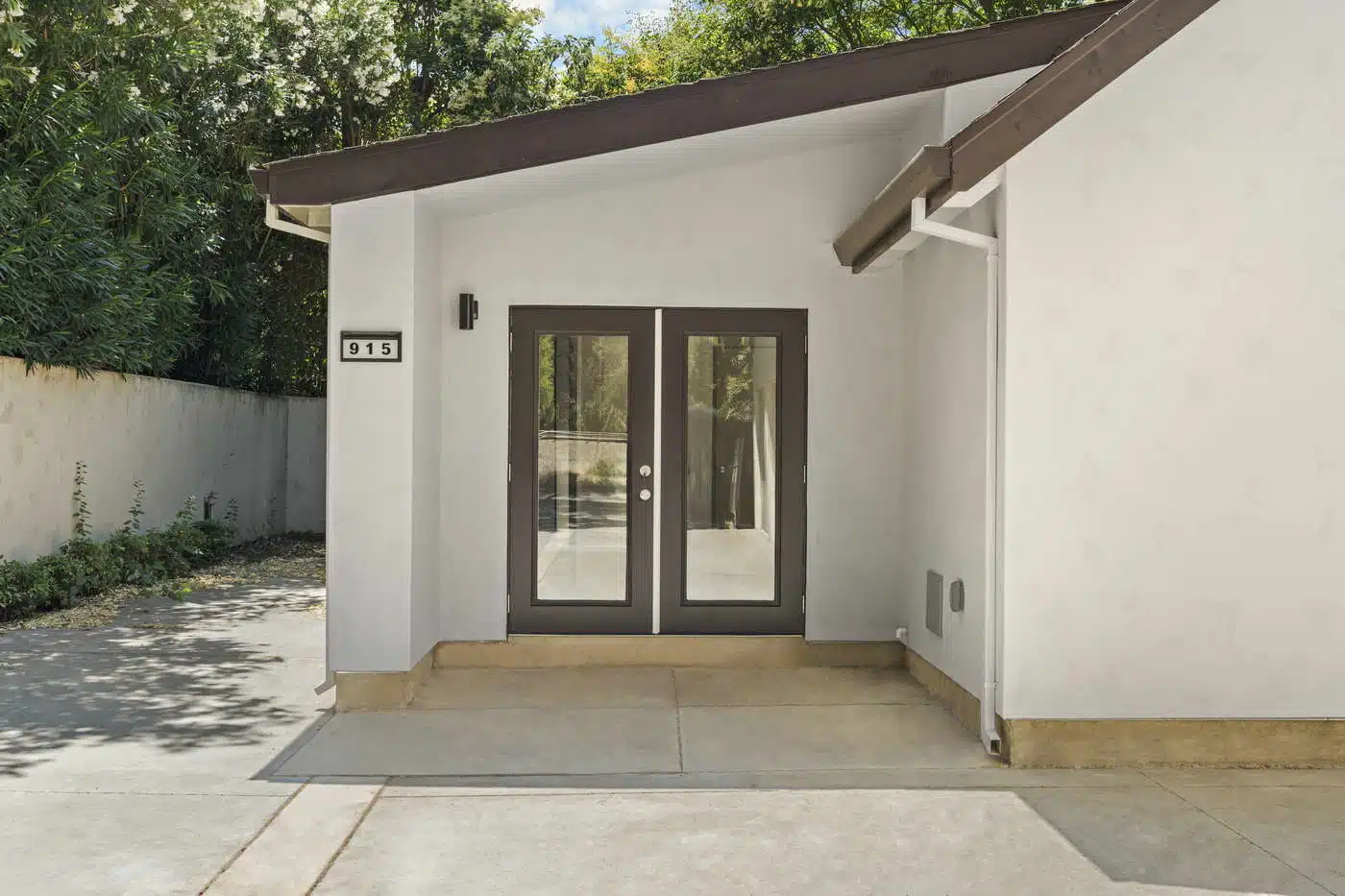 Arched recessed entry alcove with black craftsman door, glass panel, and dual wall sconces