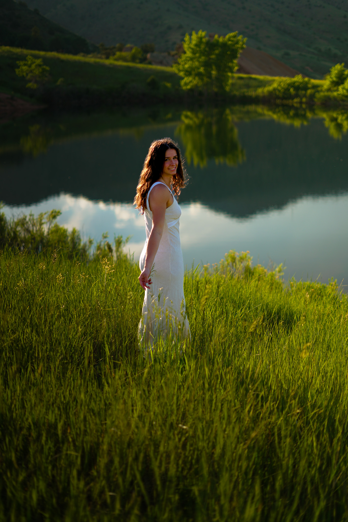Senior portrait - brunette in white dress by lake with reflections