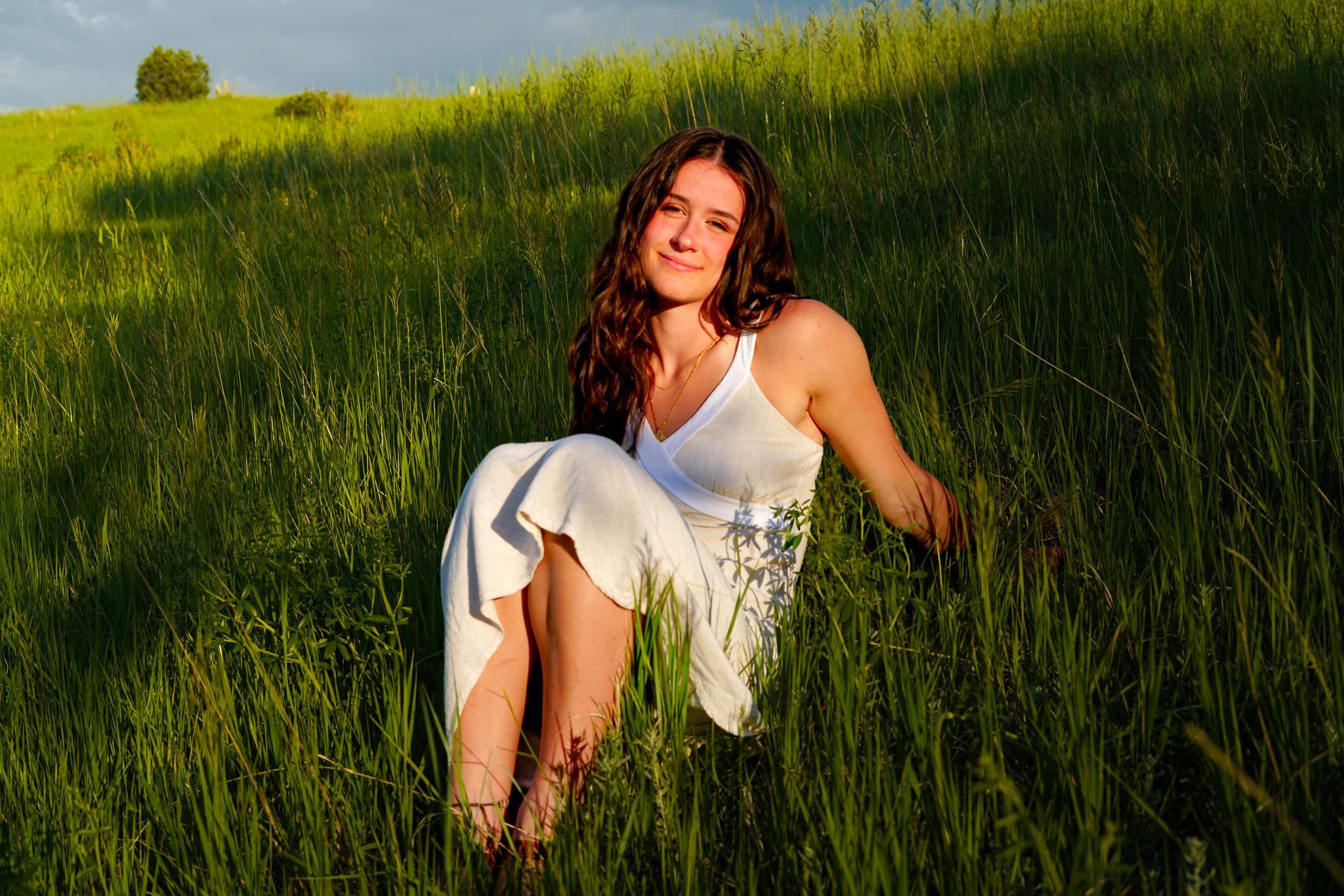 Senior portrait - brunette in white dress sitting in green grass