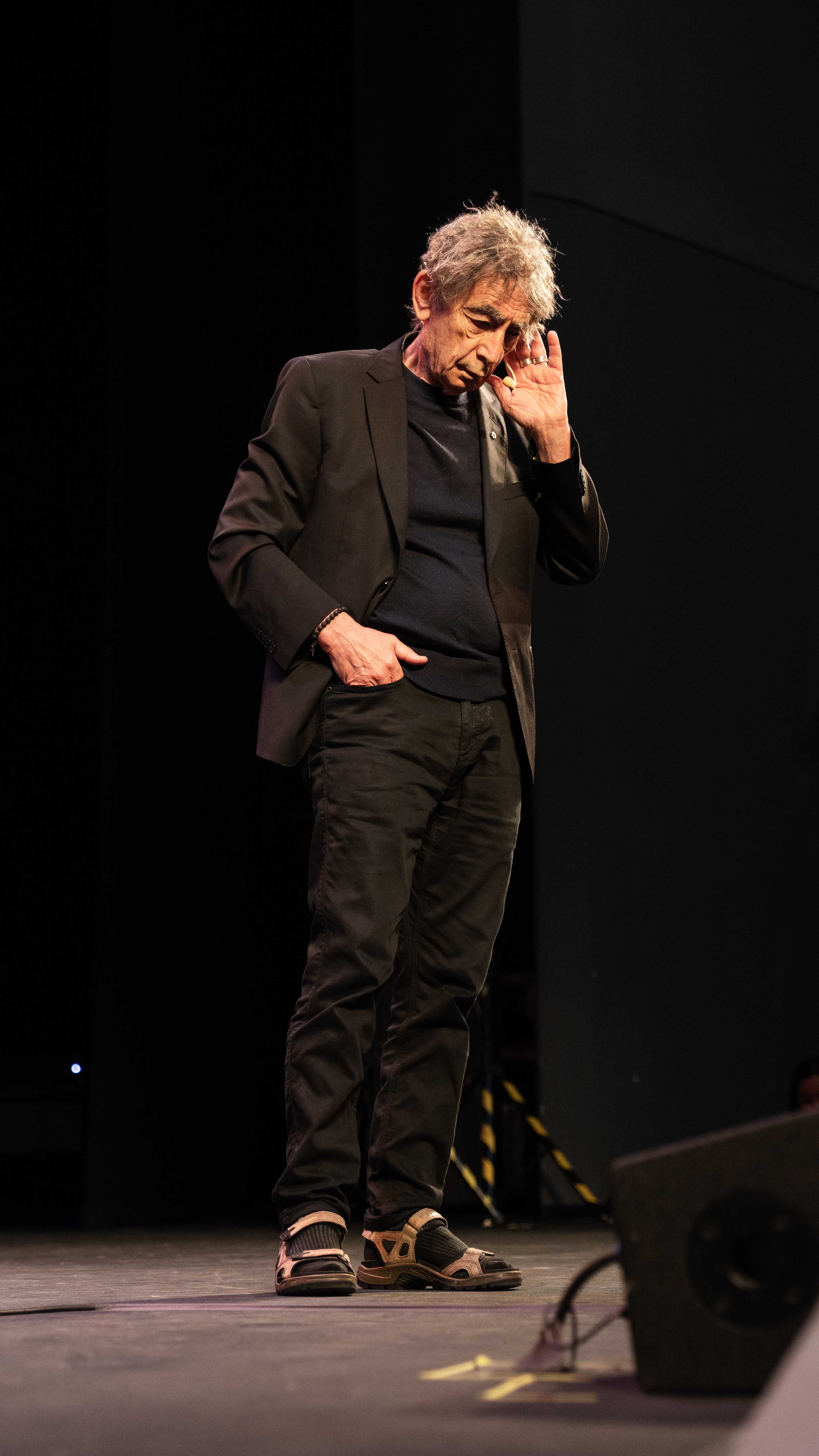 Gabor Maté de cuerpo completo en el escenario, escuchando atentamente