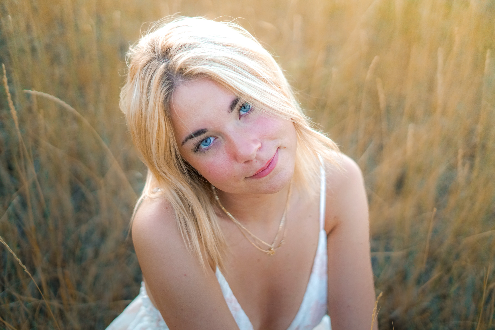 Senior portrait - close-up of blonde woman with blue eyes in field