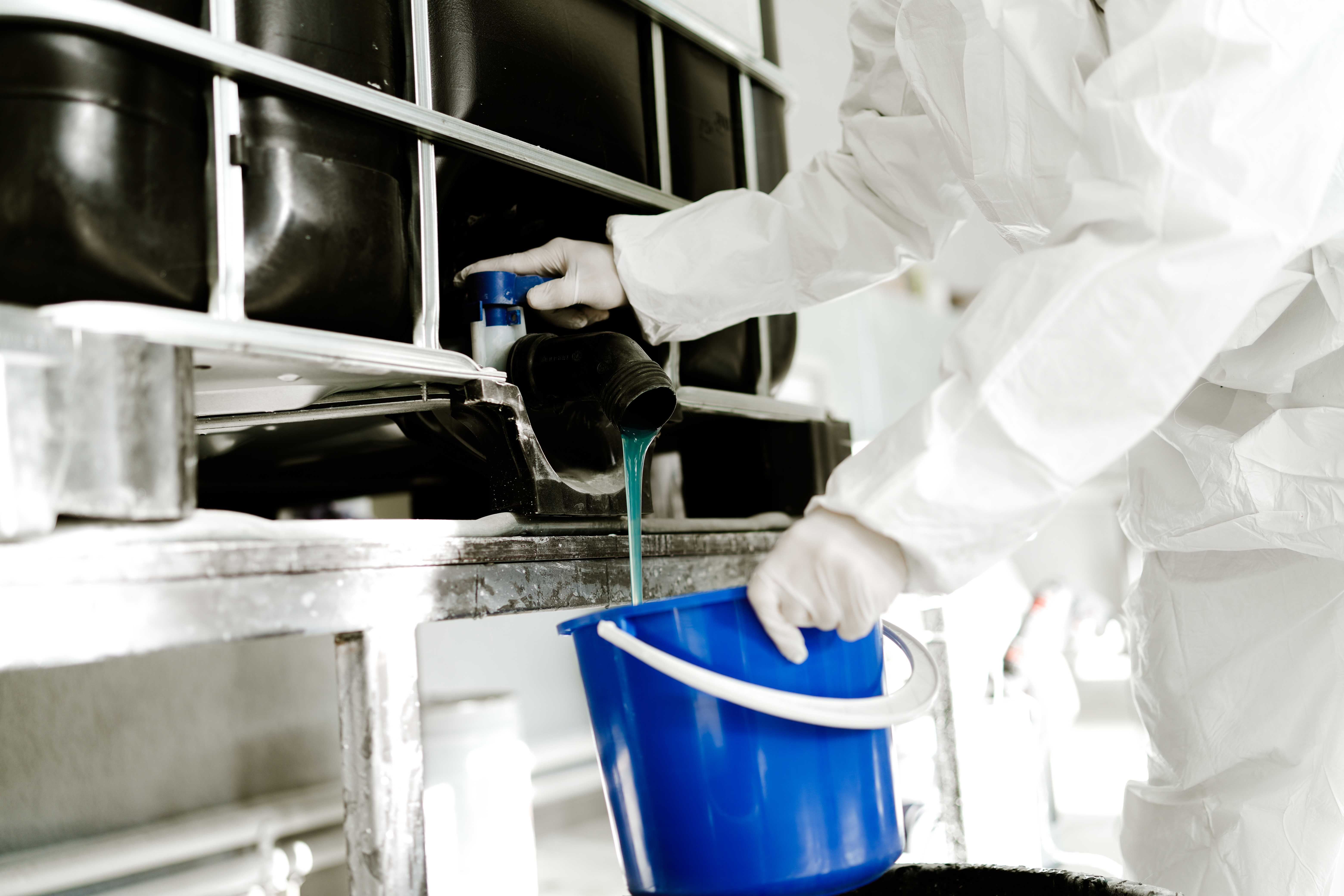 Resina versata da una vasca industriale in un secchio blu