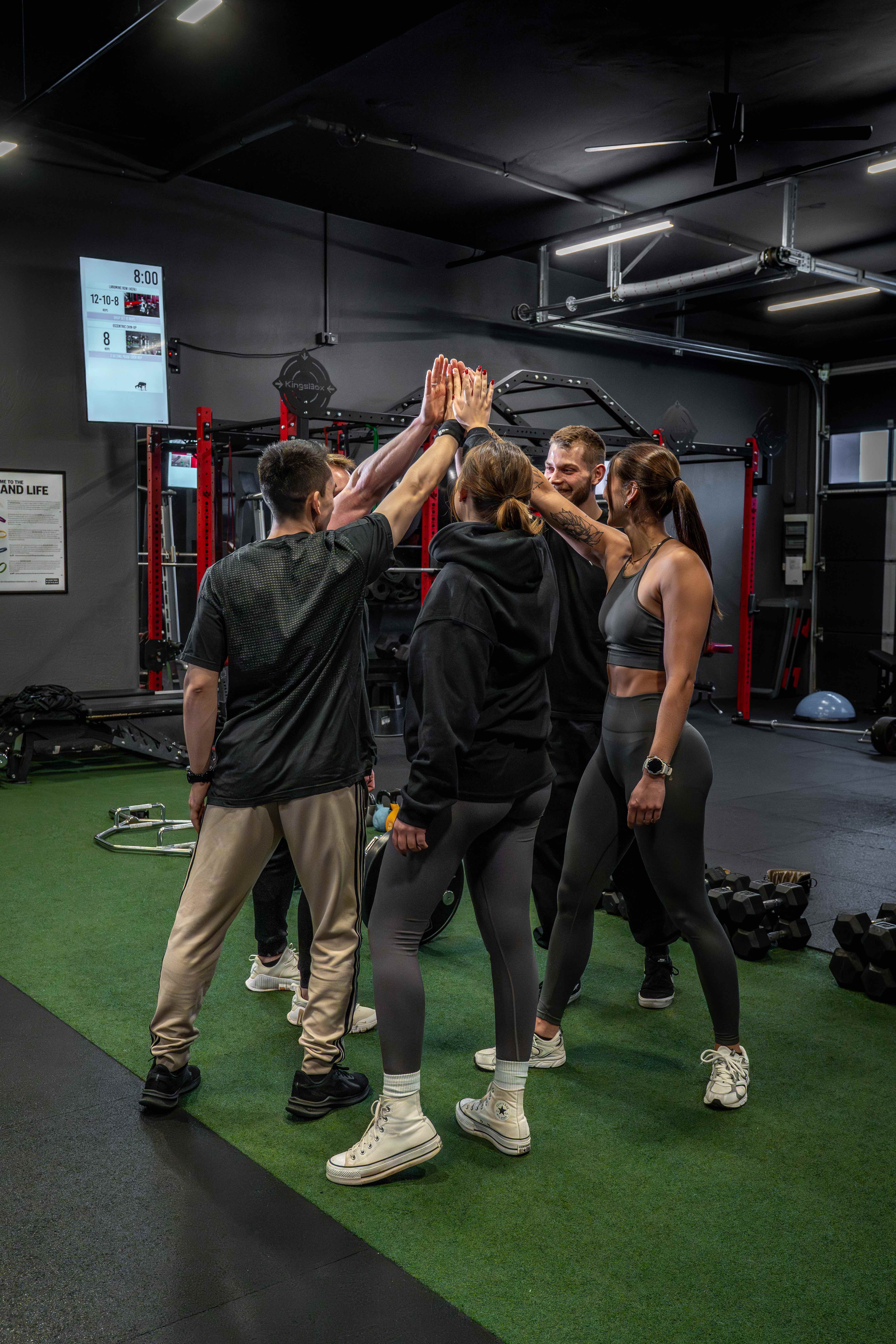Trainierende und Coach geben sich nach dem Training ein gemeinsames High-Five