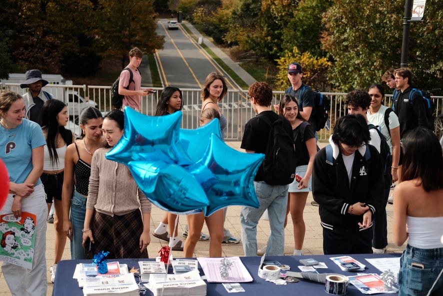 Students participating in a voter registration drive with campaign materials and blue star balloons