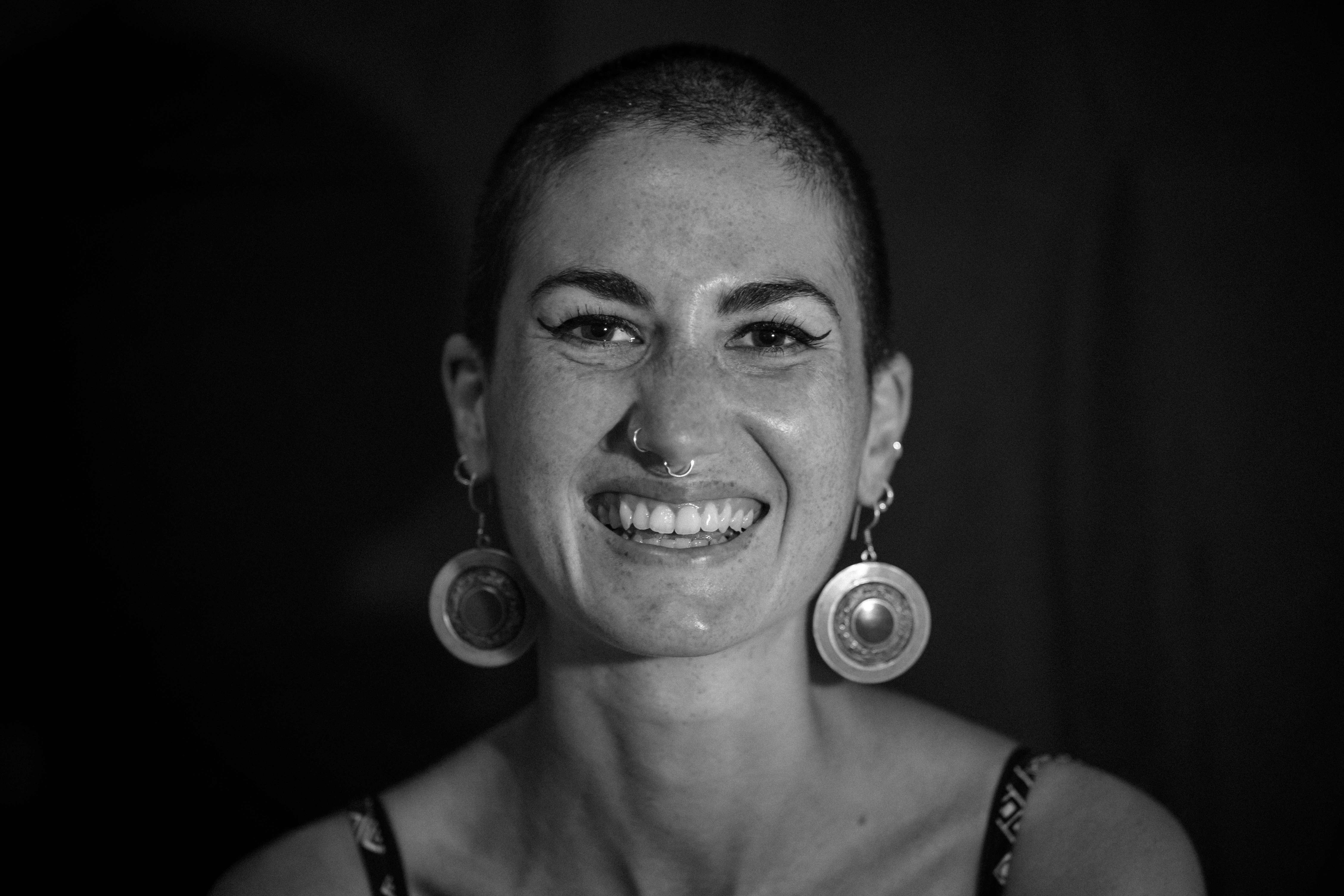 Smiling woman with shaved head and circular earrings