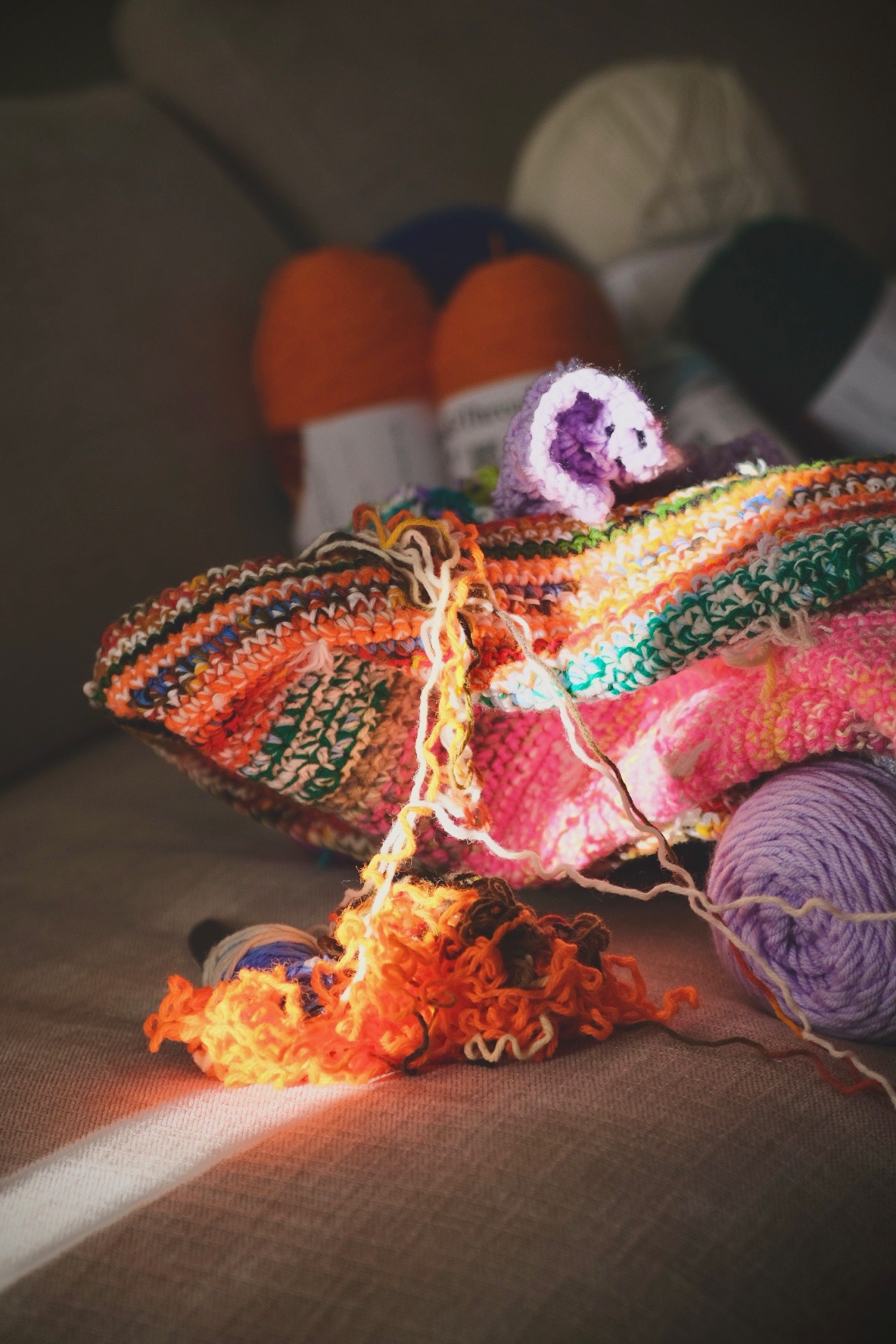 Colorful yarn skeins and crochet pieces in warm sunlight