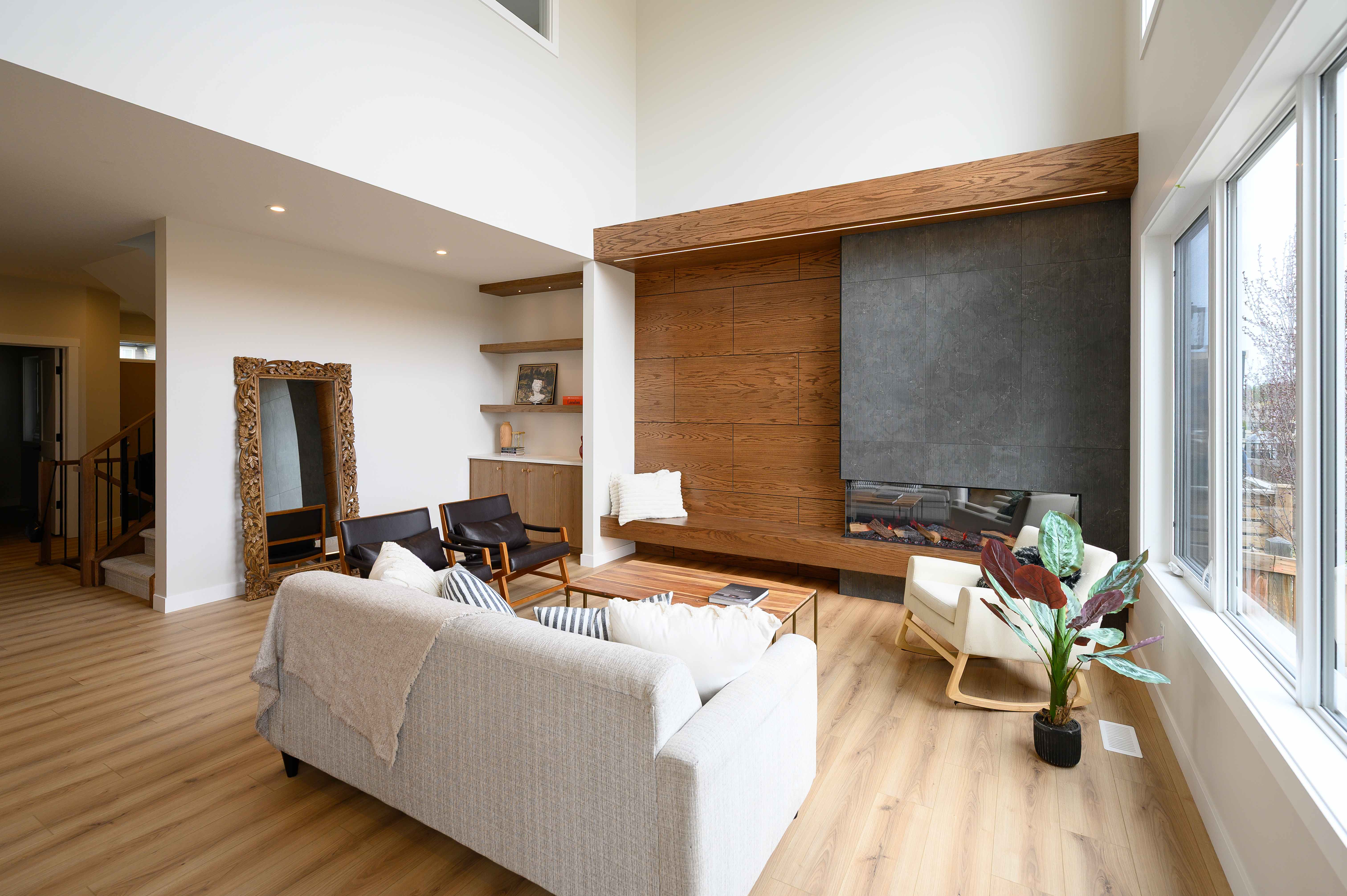 Double-height living room with a wood-panelled feature wall and stone fireplace in a Danson custom home