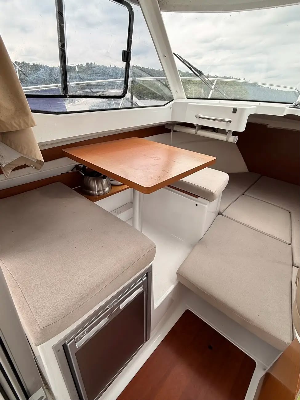 The saloon dinette with wooden table, bench seating and galley fridge