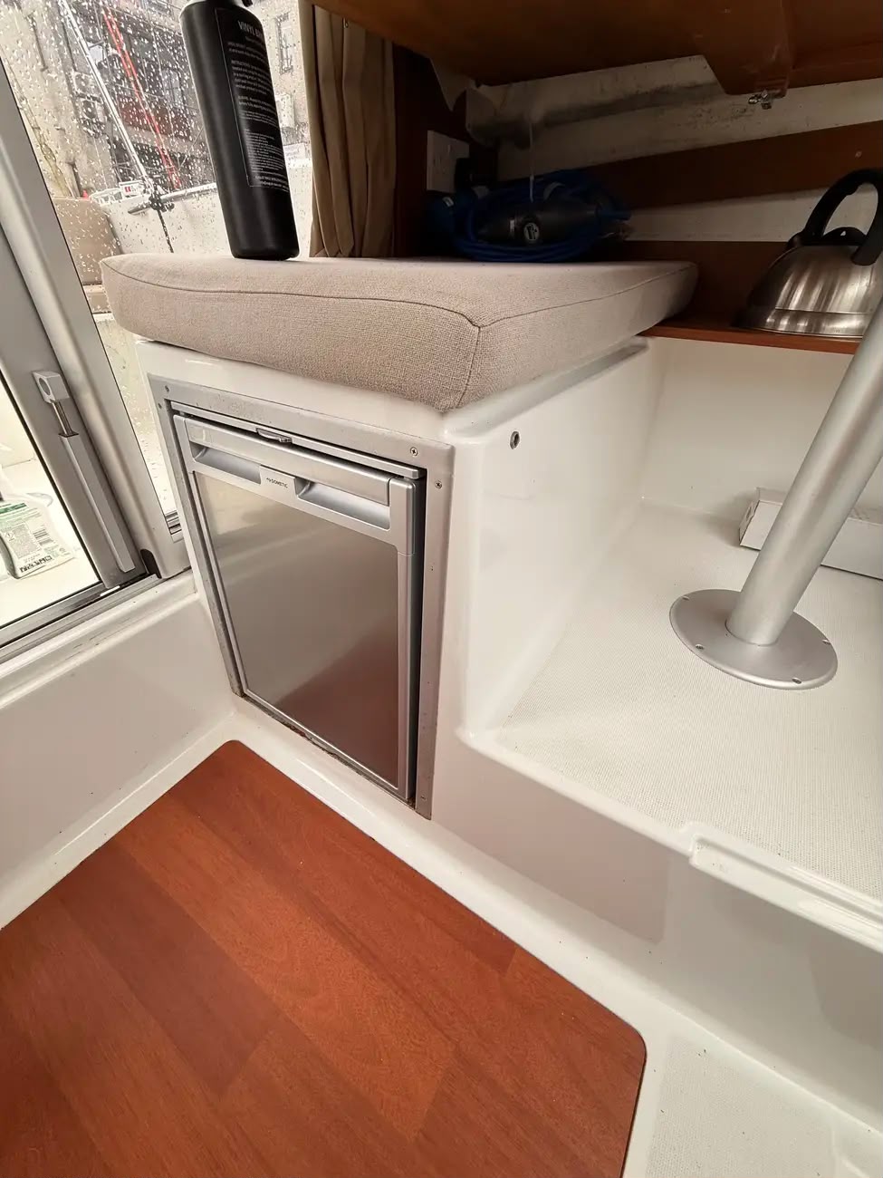 The galley area with a stainless Dometic fridge and cushioned seat