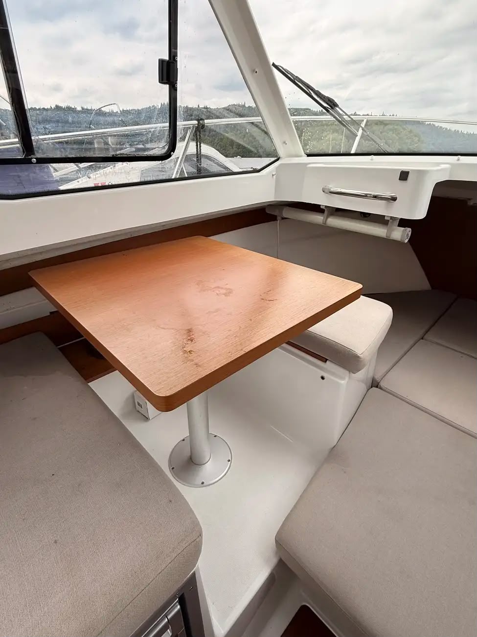 The wooden dinette table and wraparound seating below the wheelhouse windows